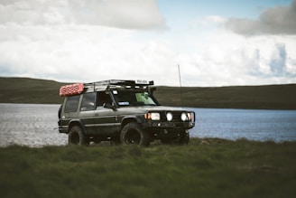 An off-road vehicle parks by the water.