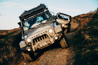 Two jeeps are driving off-road, covered in mud.
