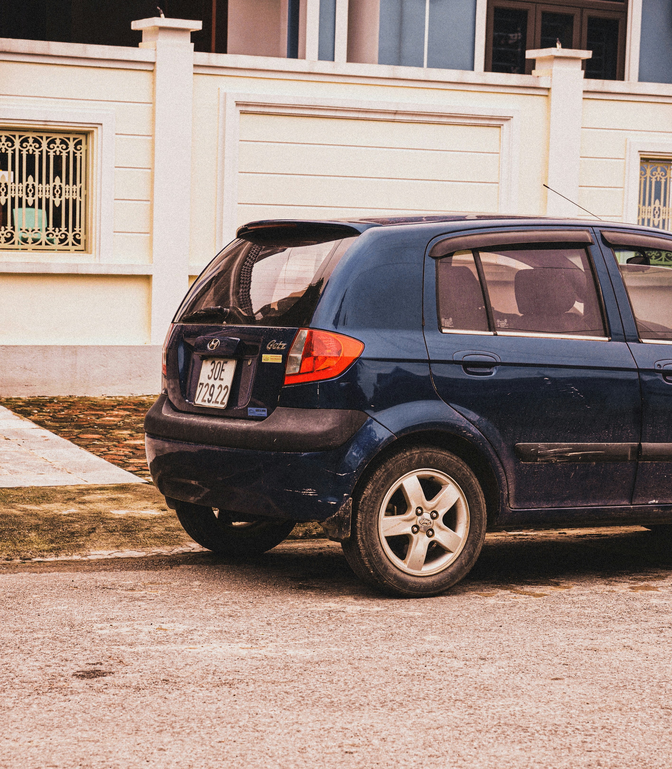 A blue car is parked near a building.