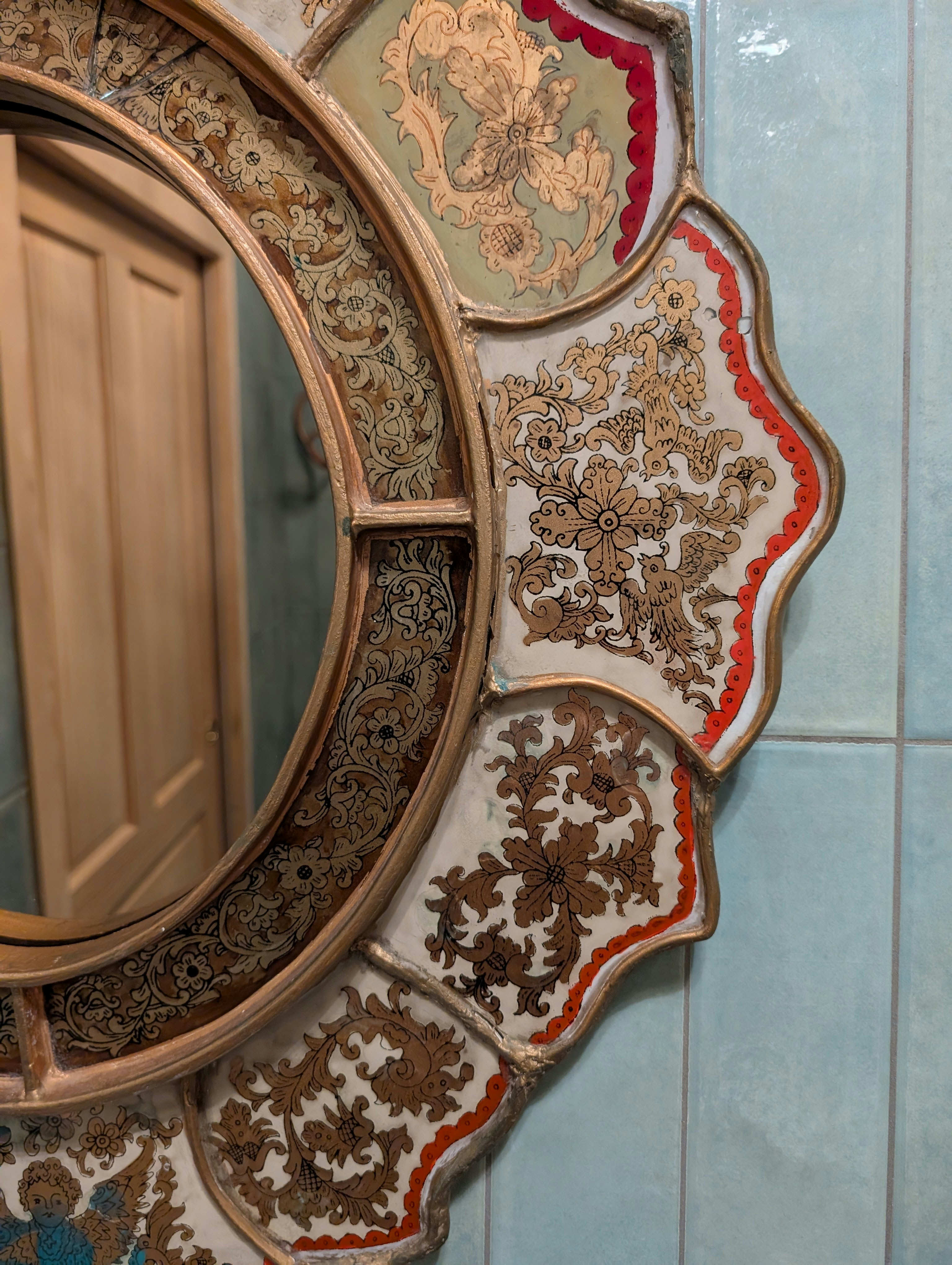 An ornate mirror is hanging on a light blue wall.