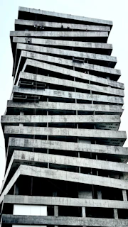 Twisted, unfinished concrete building against a white sky.