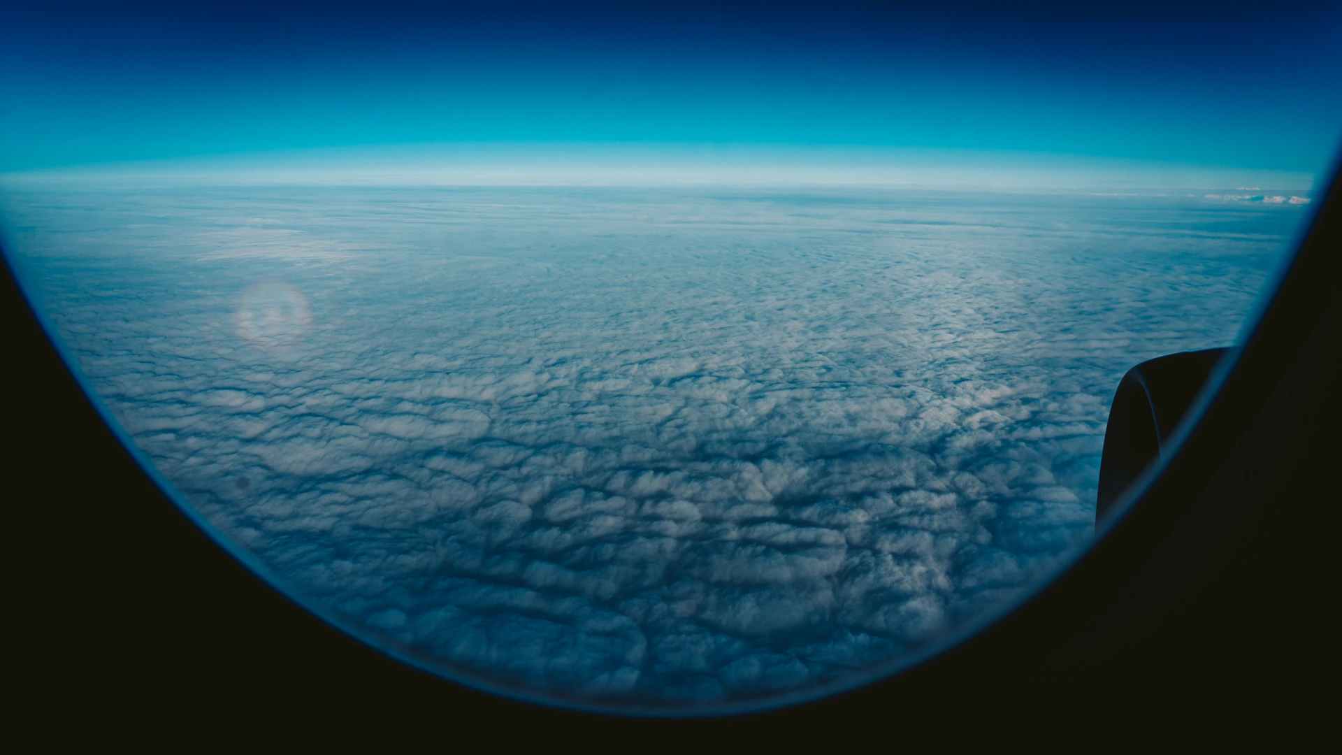 Clouds and blue sky seen through an airplane window.