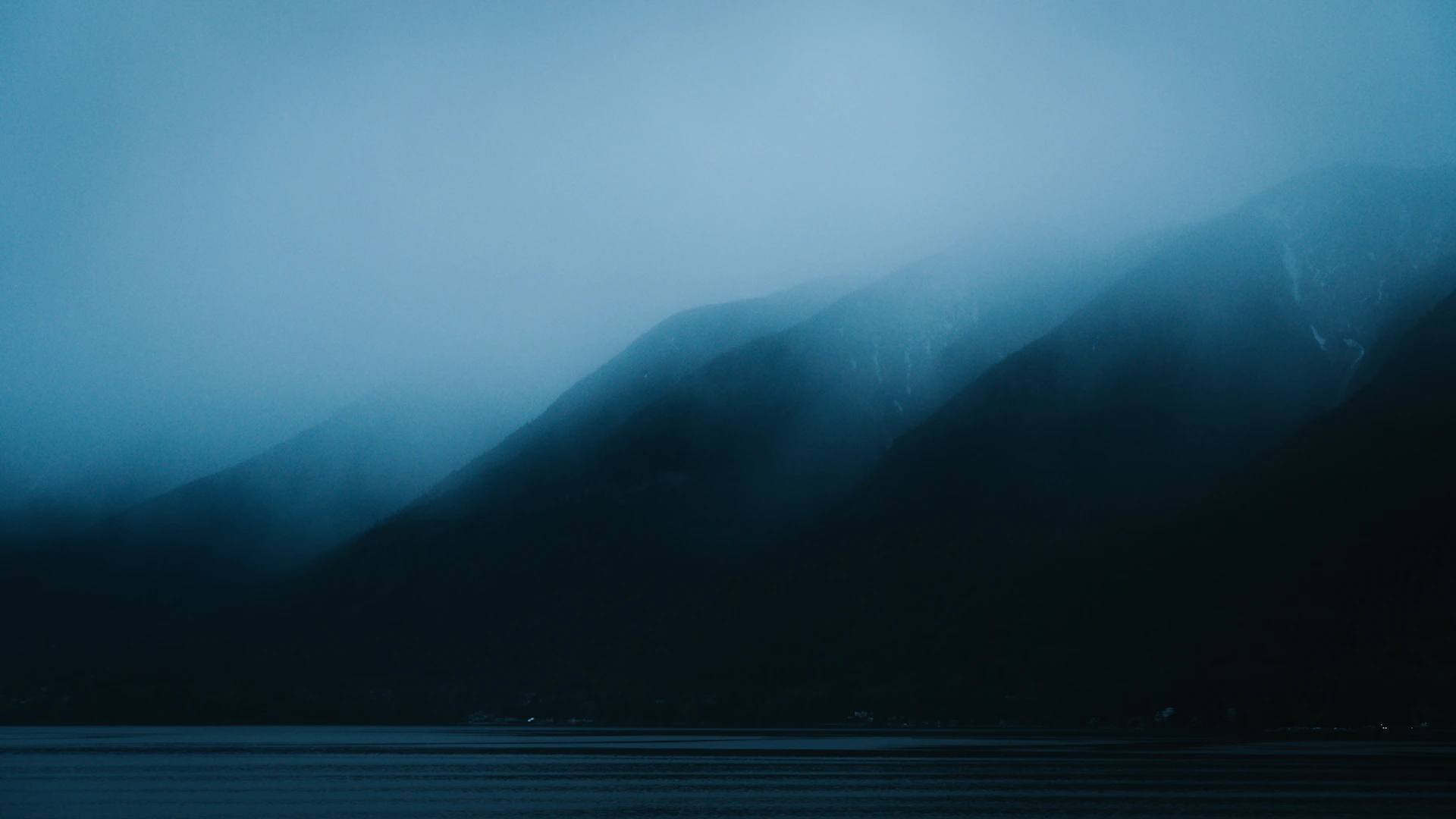 Foggy mountains are shrouded in a blue mist.