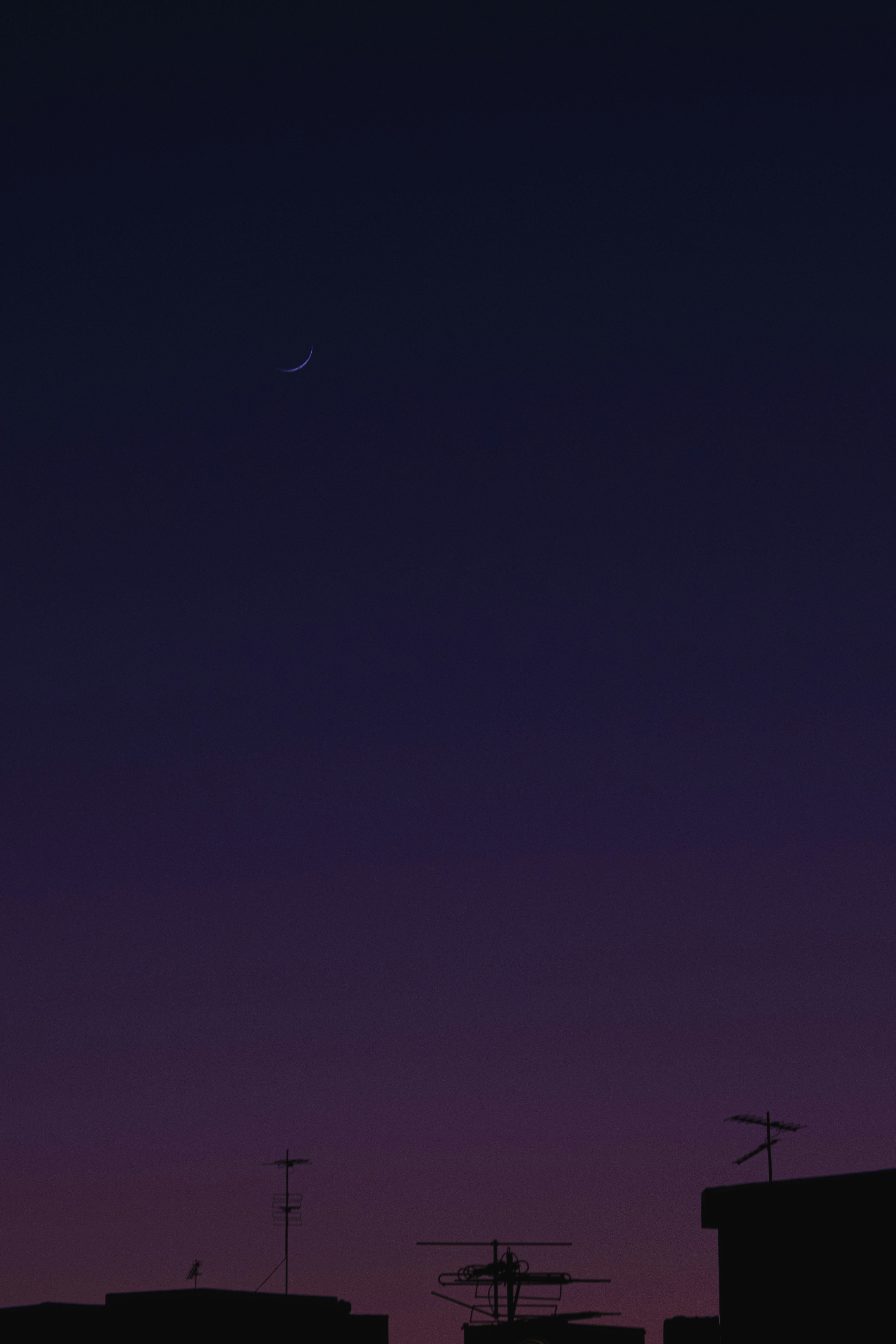 Nighttime cityscape with a crescent moon visible.