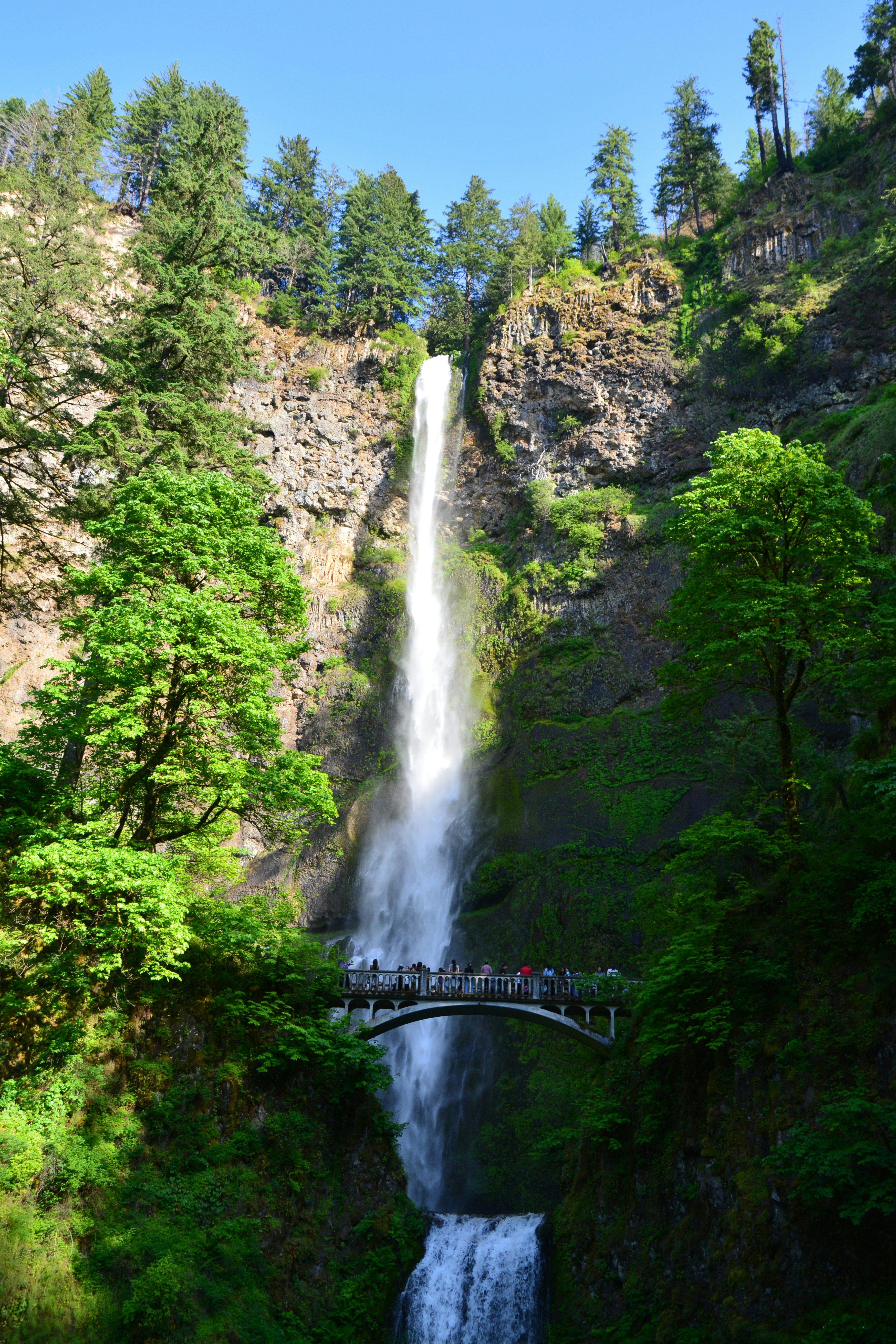 A tall waterfall cascades over a bridge.