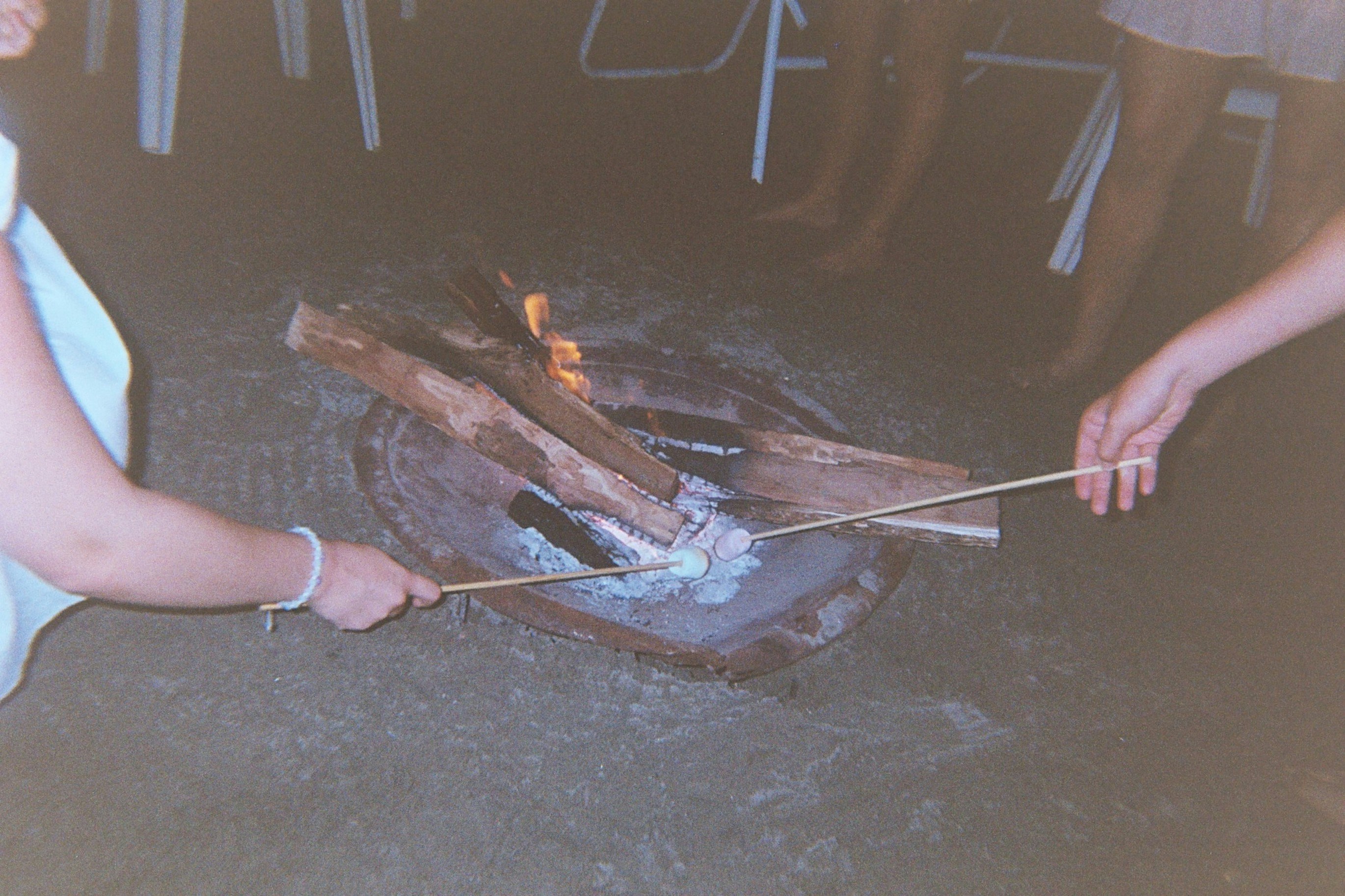 People are roasting marshmallows over a campfire.