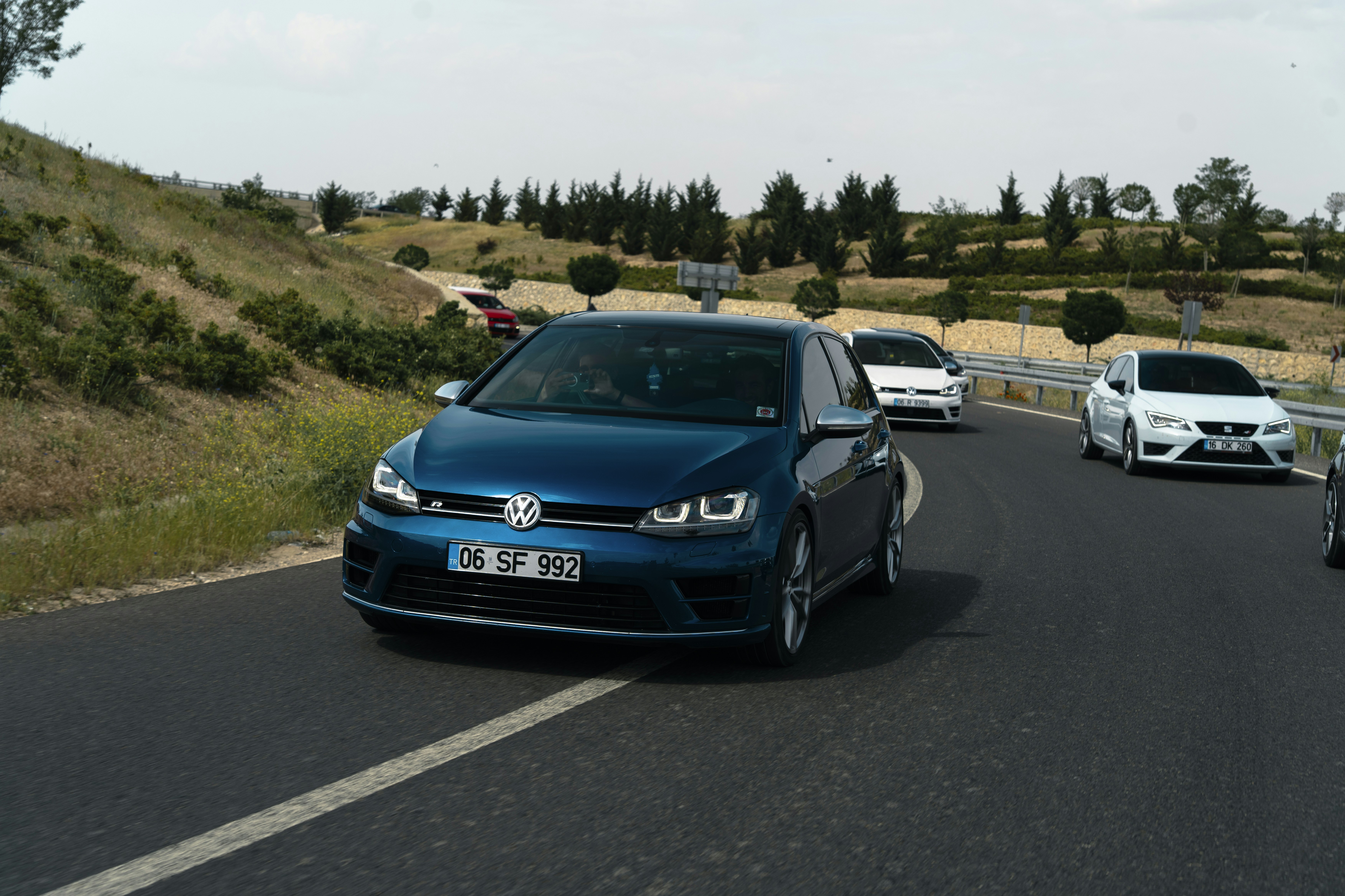 A blue car drives down a road with others.