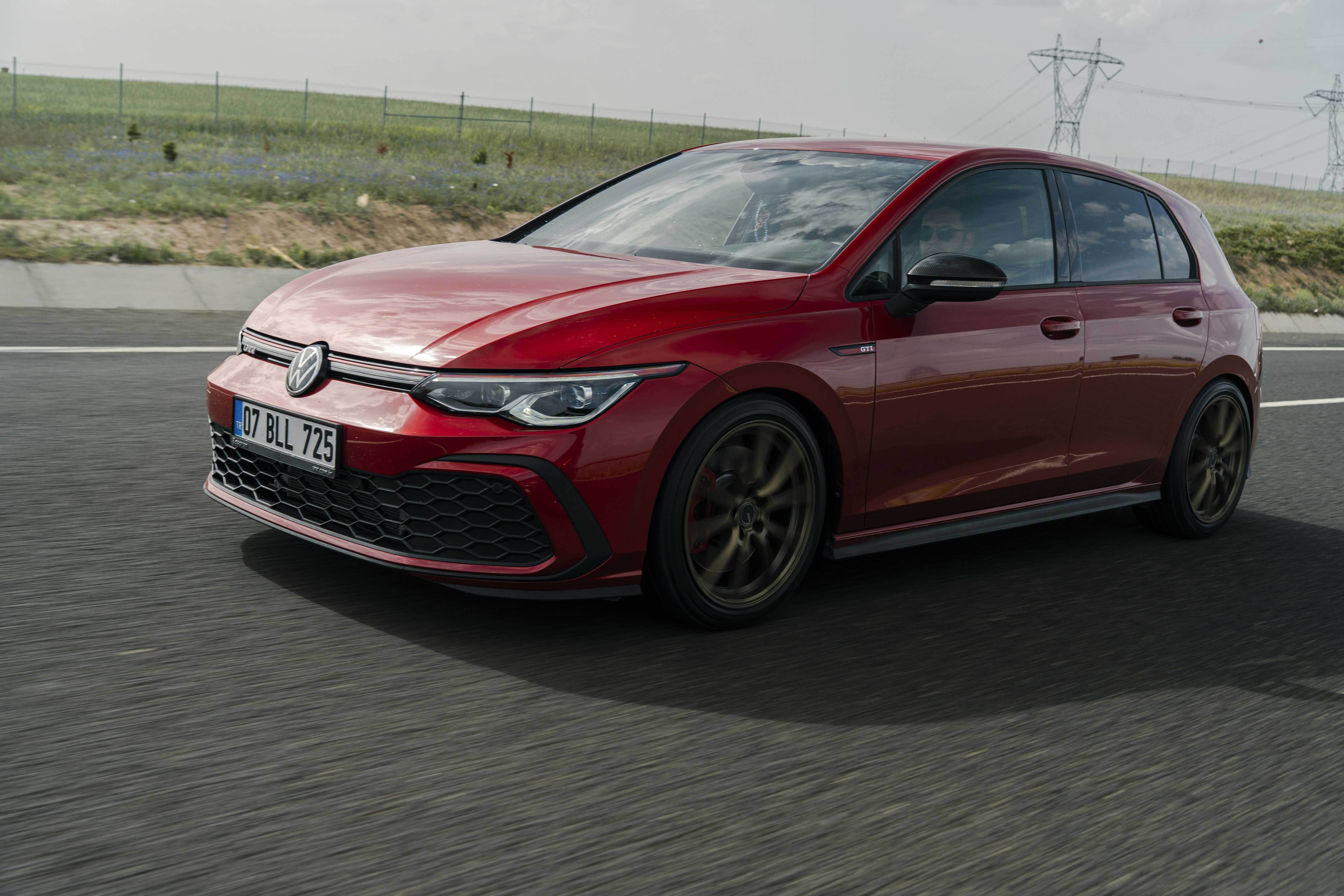 A red volkswagen golf driving on the road.