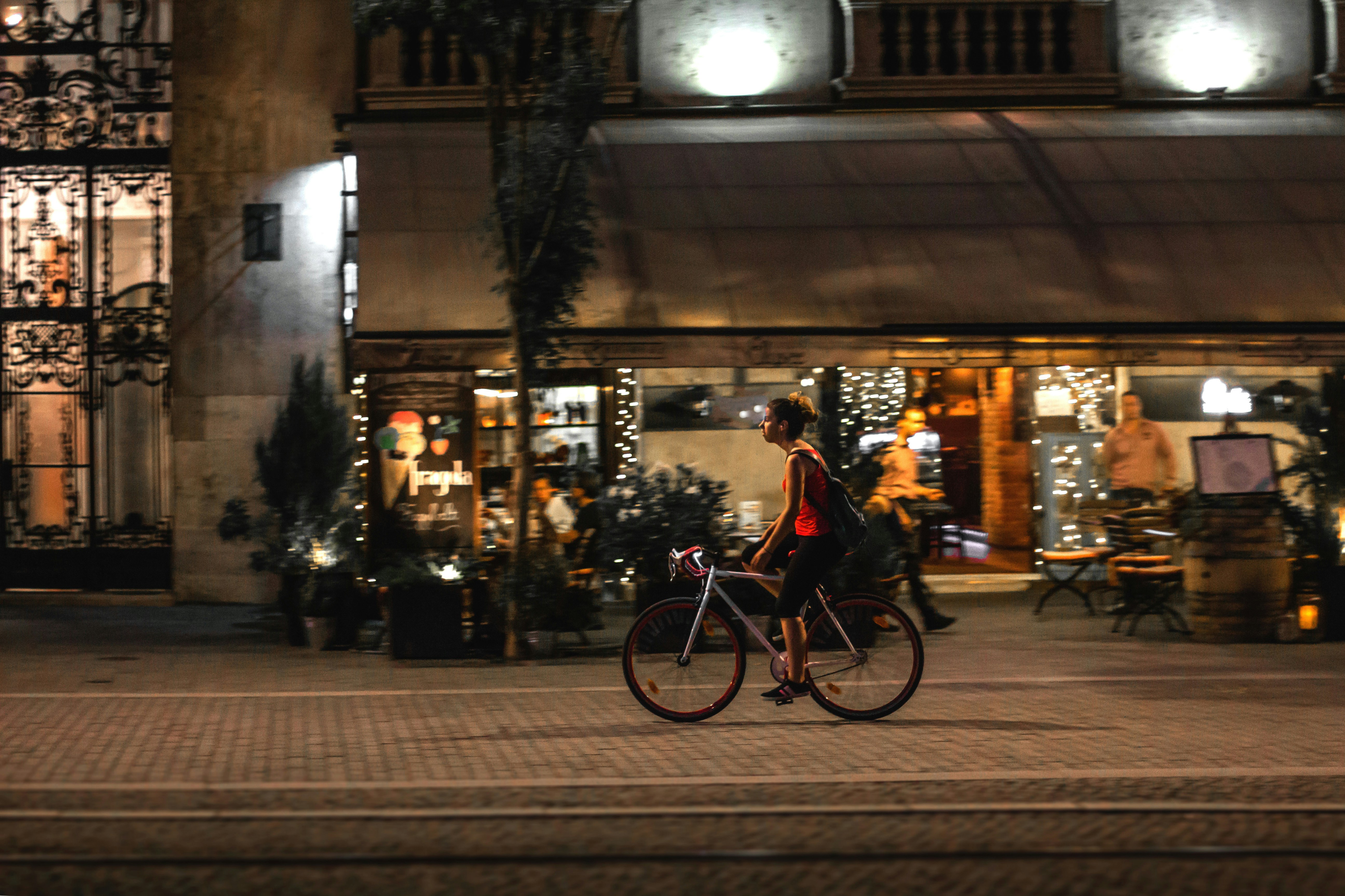 A cyclist rides past a restaurant at night.