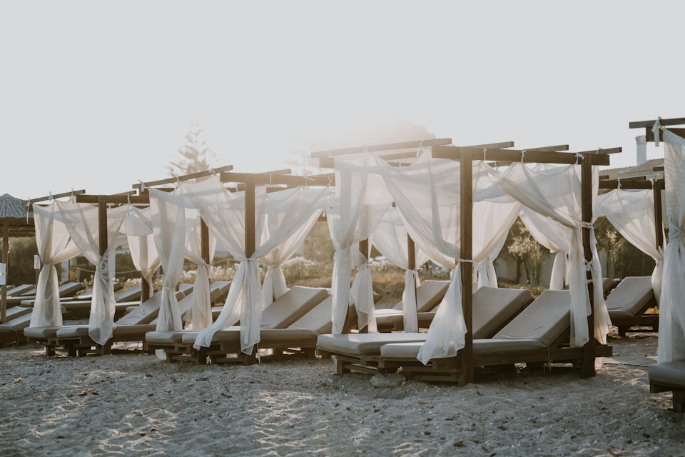 Rows of lounge chairs and sun umbrellas line a serene sandy beach scene outdoors