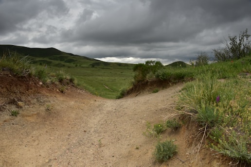 A dusty trail leads into a green valley.