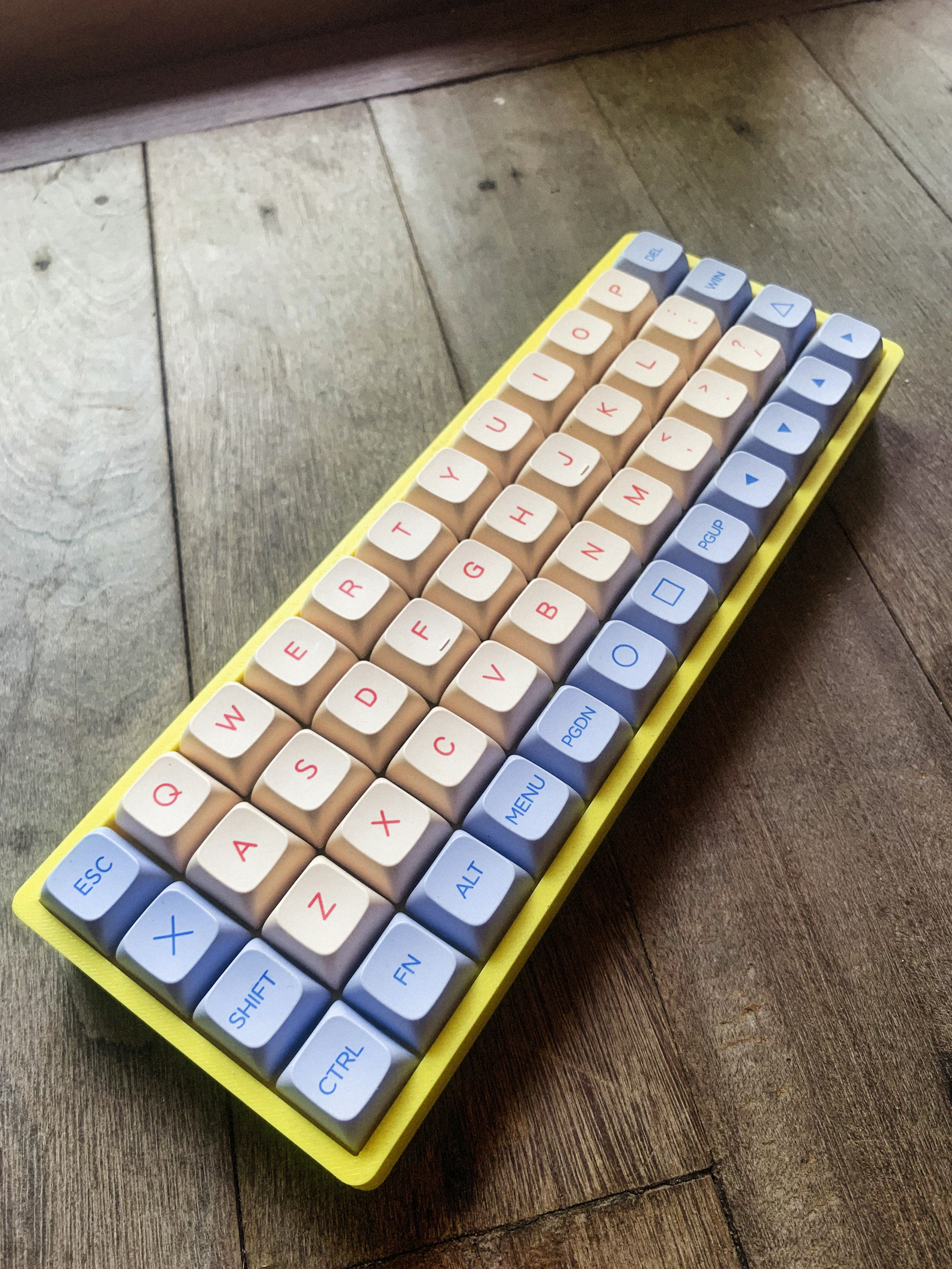A small keyboard in a yellow case with its keys in straight columns, on a wooden surface