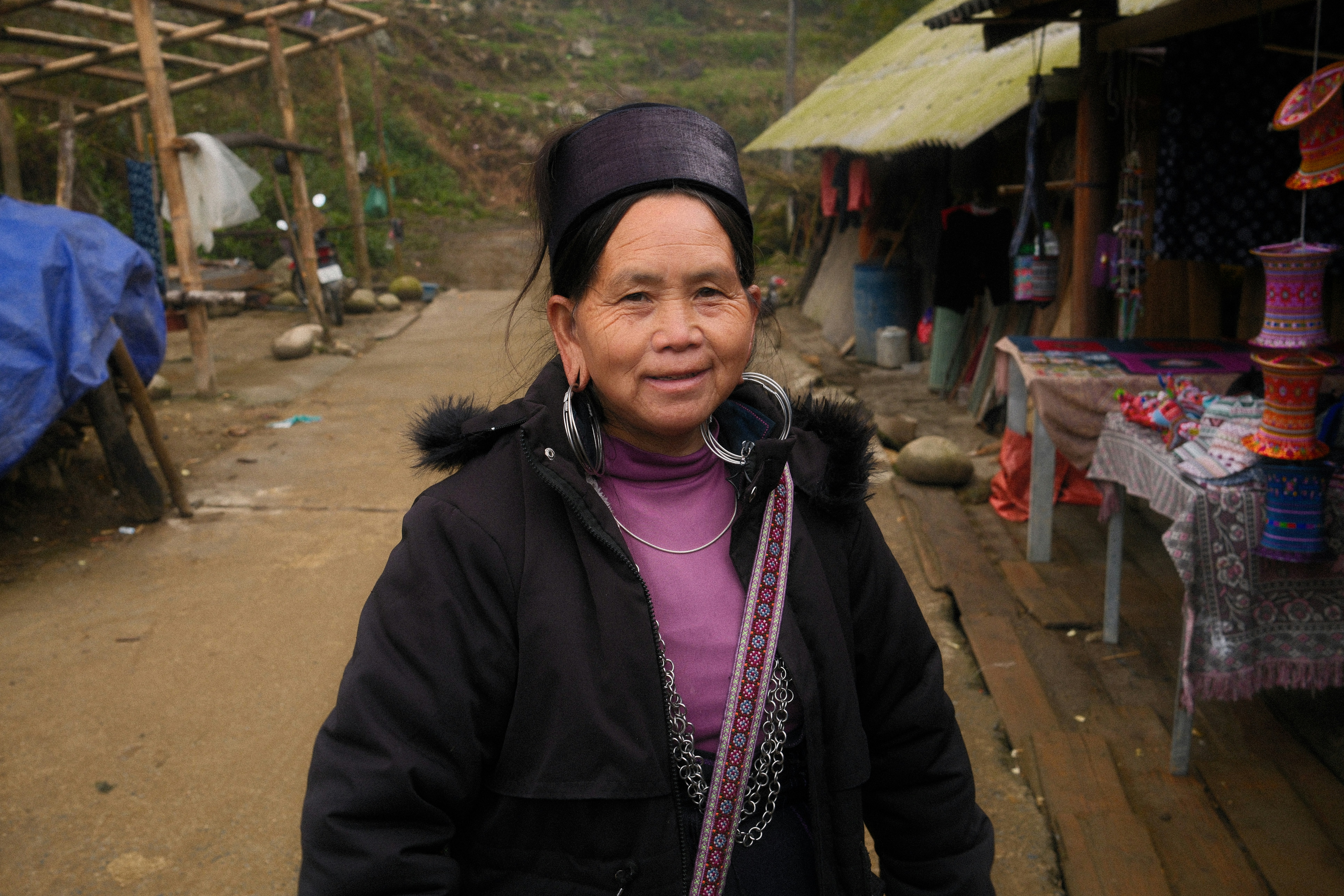 A woman smiles near some shops.