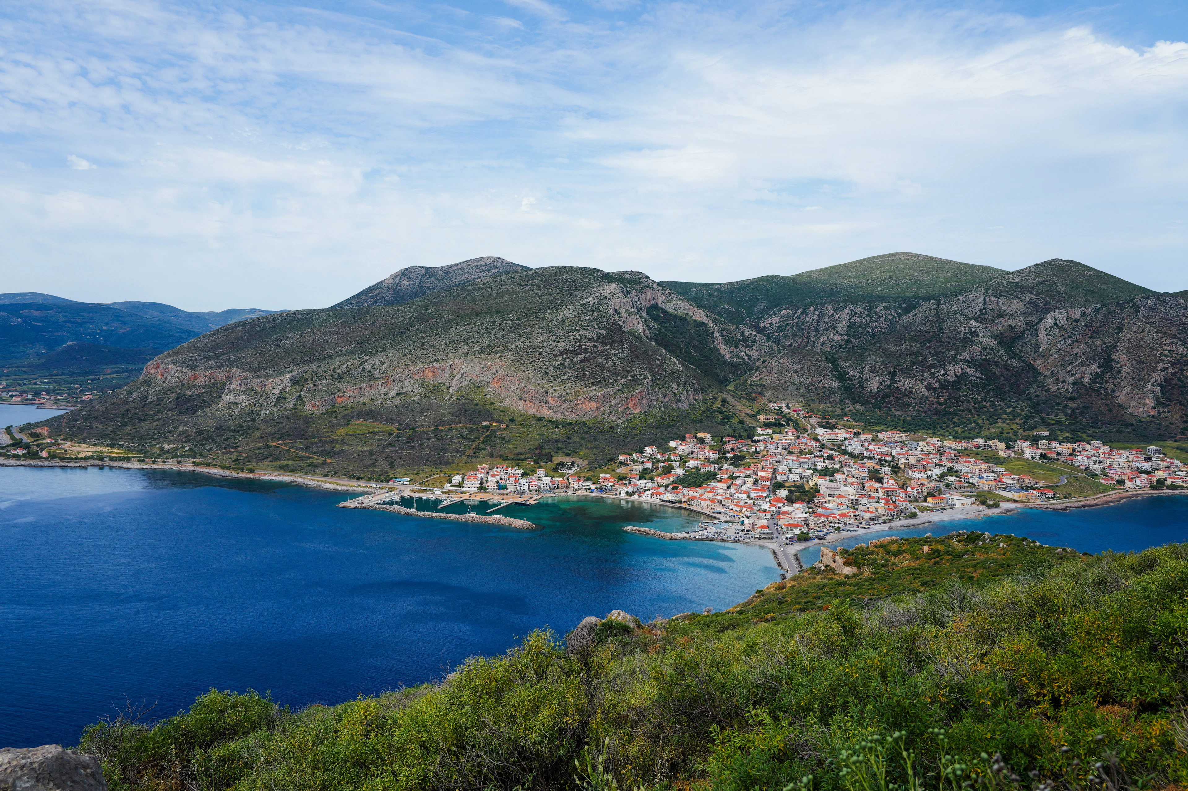 A small coastal town on a blue bay below green mountains, Greece