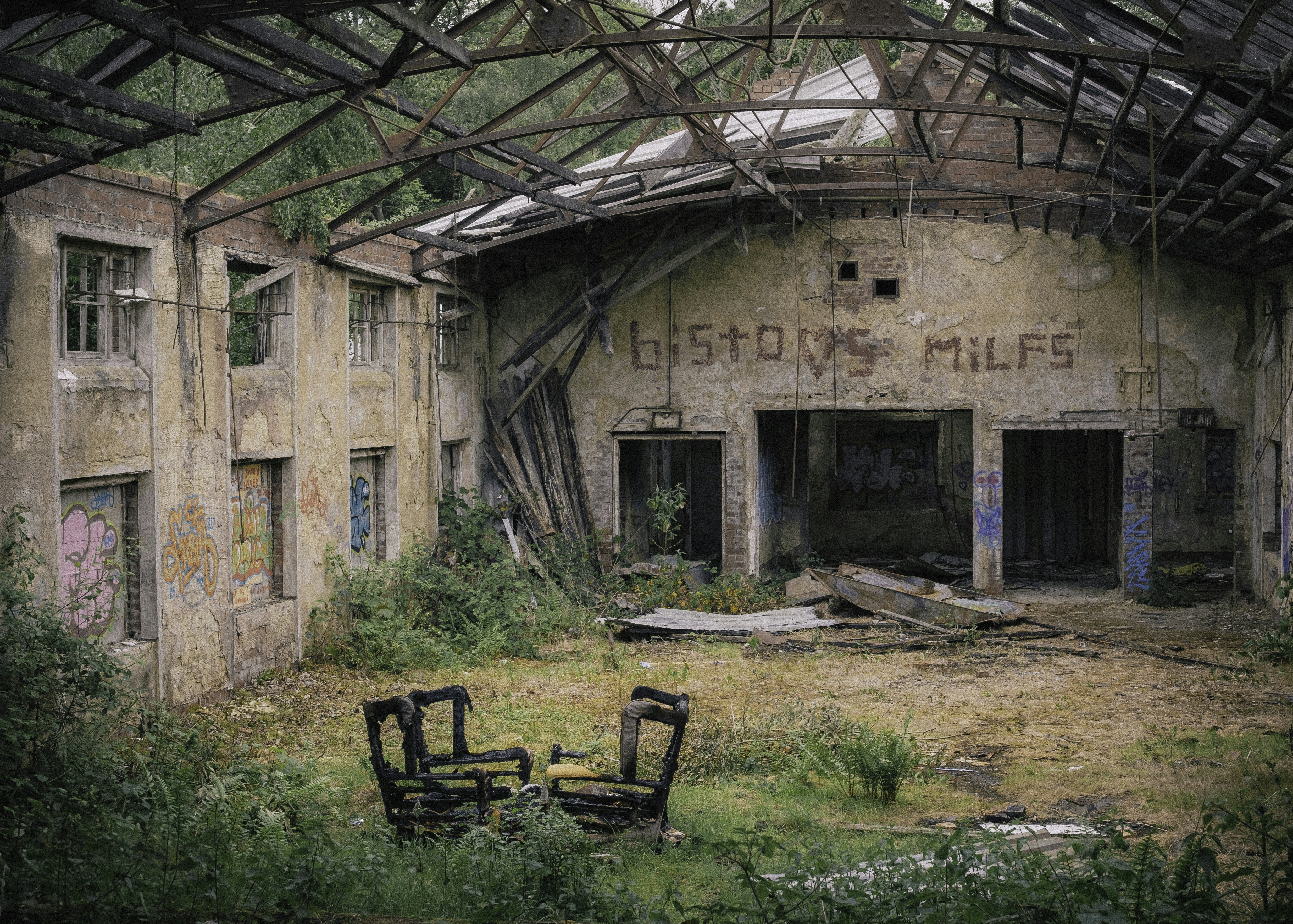 Abandoned building with overgrown plants and graffiti.