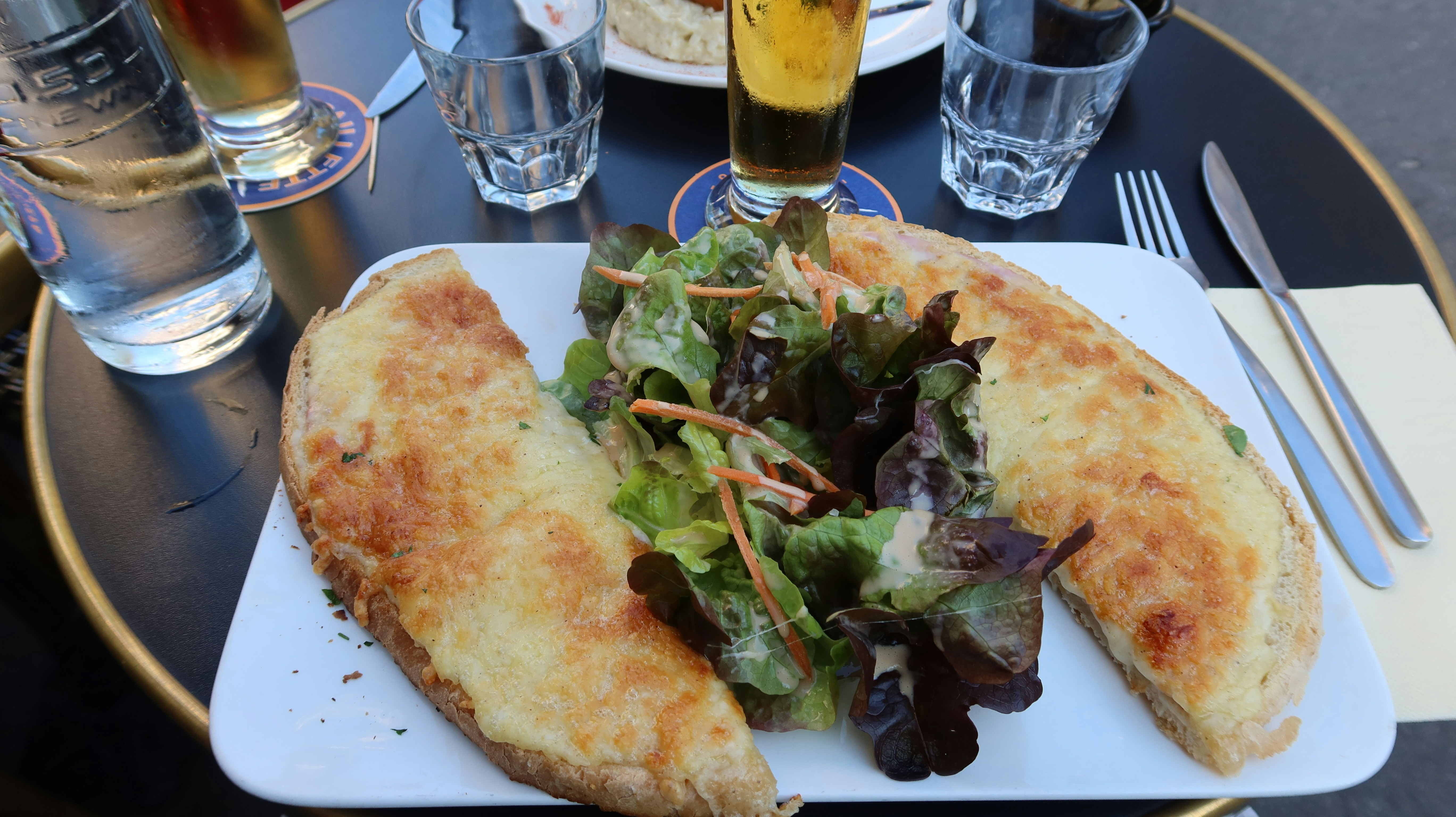 A sandwich and salad with drinks on a table.