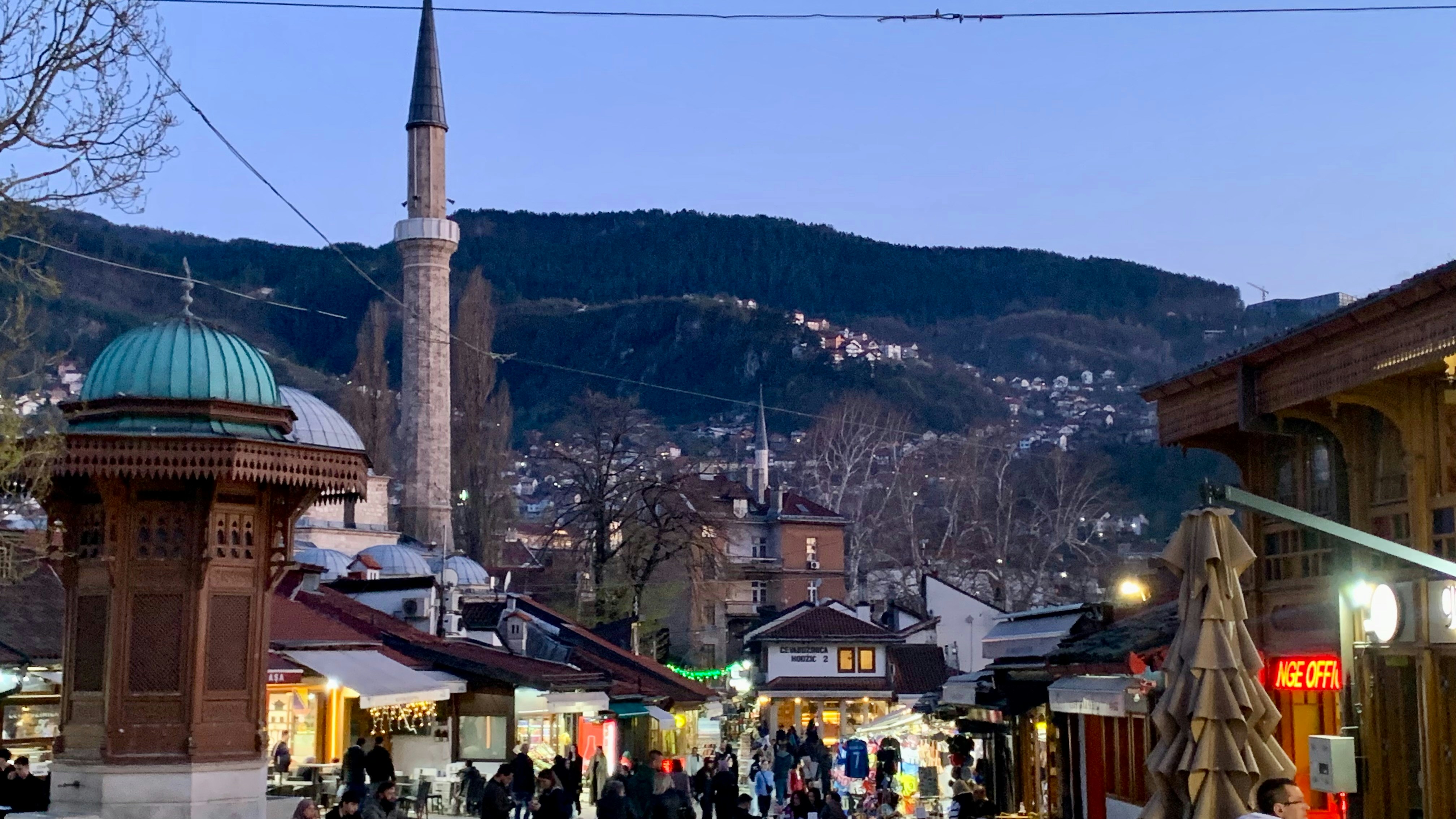 A bustling city street with a mosque in the background.