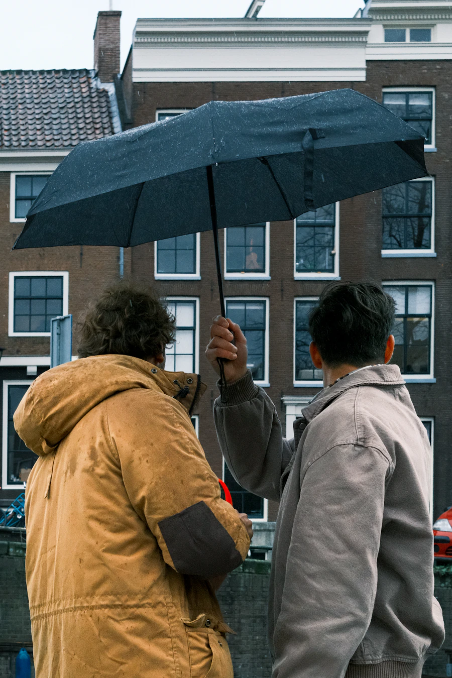Zwei Menschen teilen sich einen Regenschirm im Regen