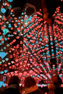 People look up at a glowing, colorful light installation.