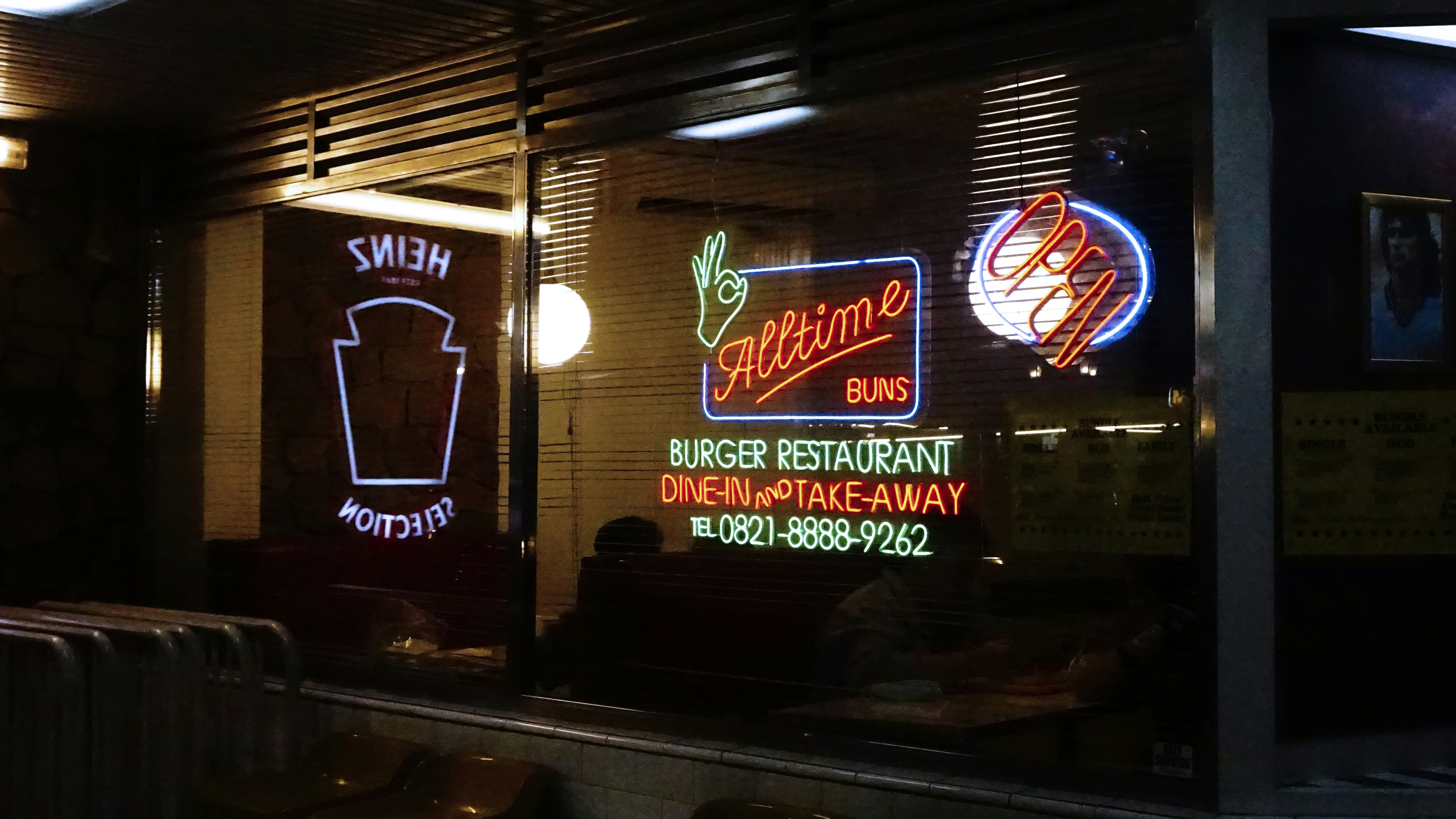 A neon sign advertises a burger restaurant at night.