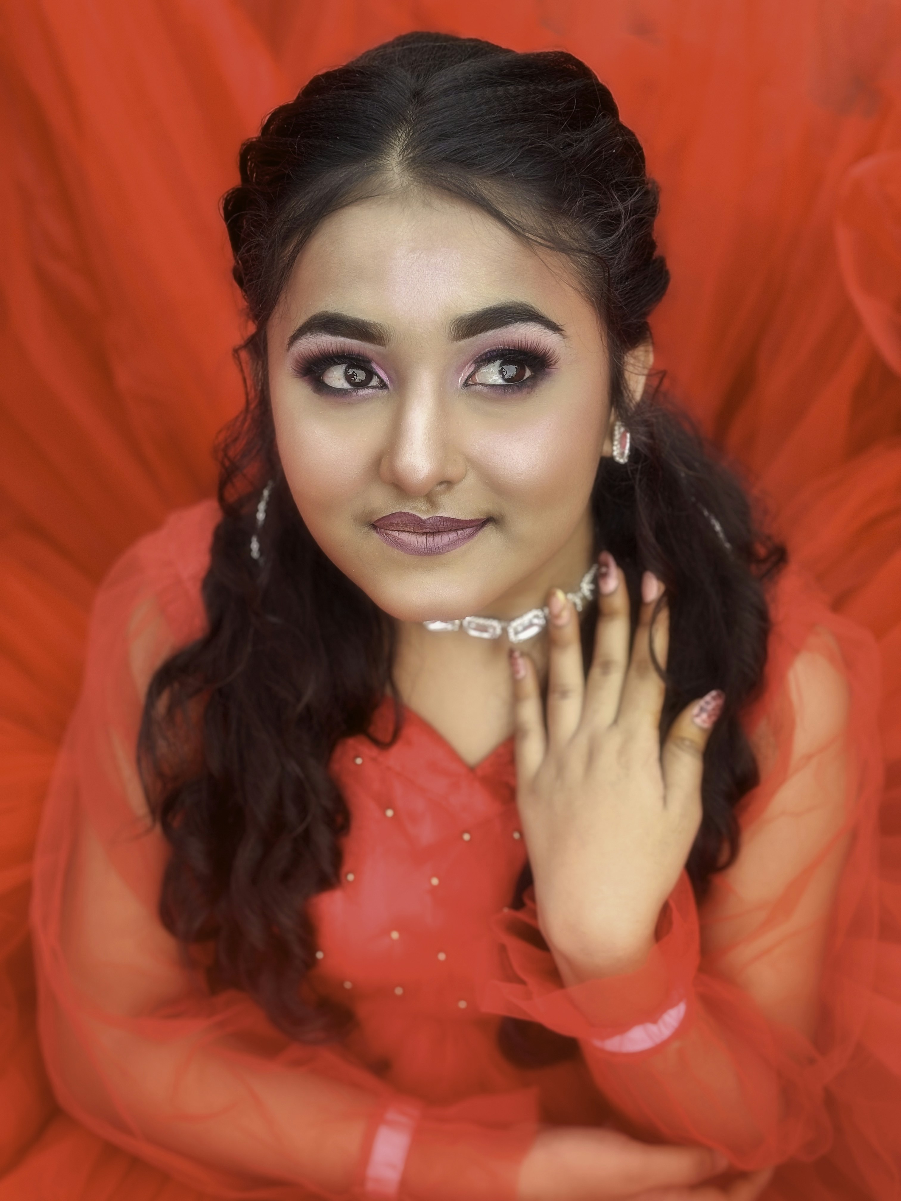 Wanita cantik berpose dengan latar belakang merah.