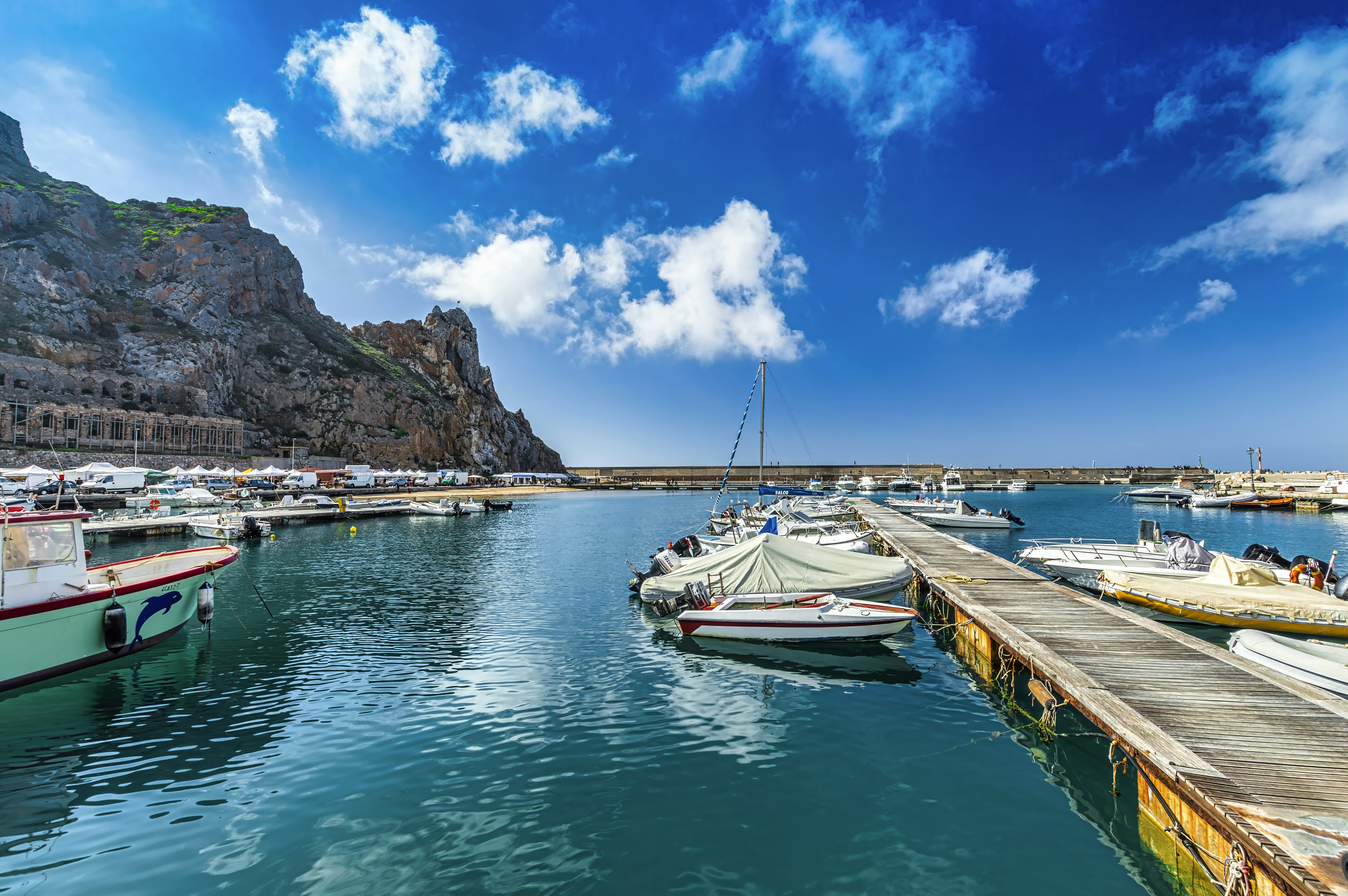 Boats are docked in a harbor under a bright sky.