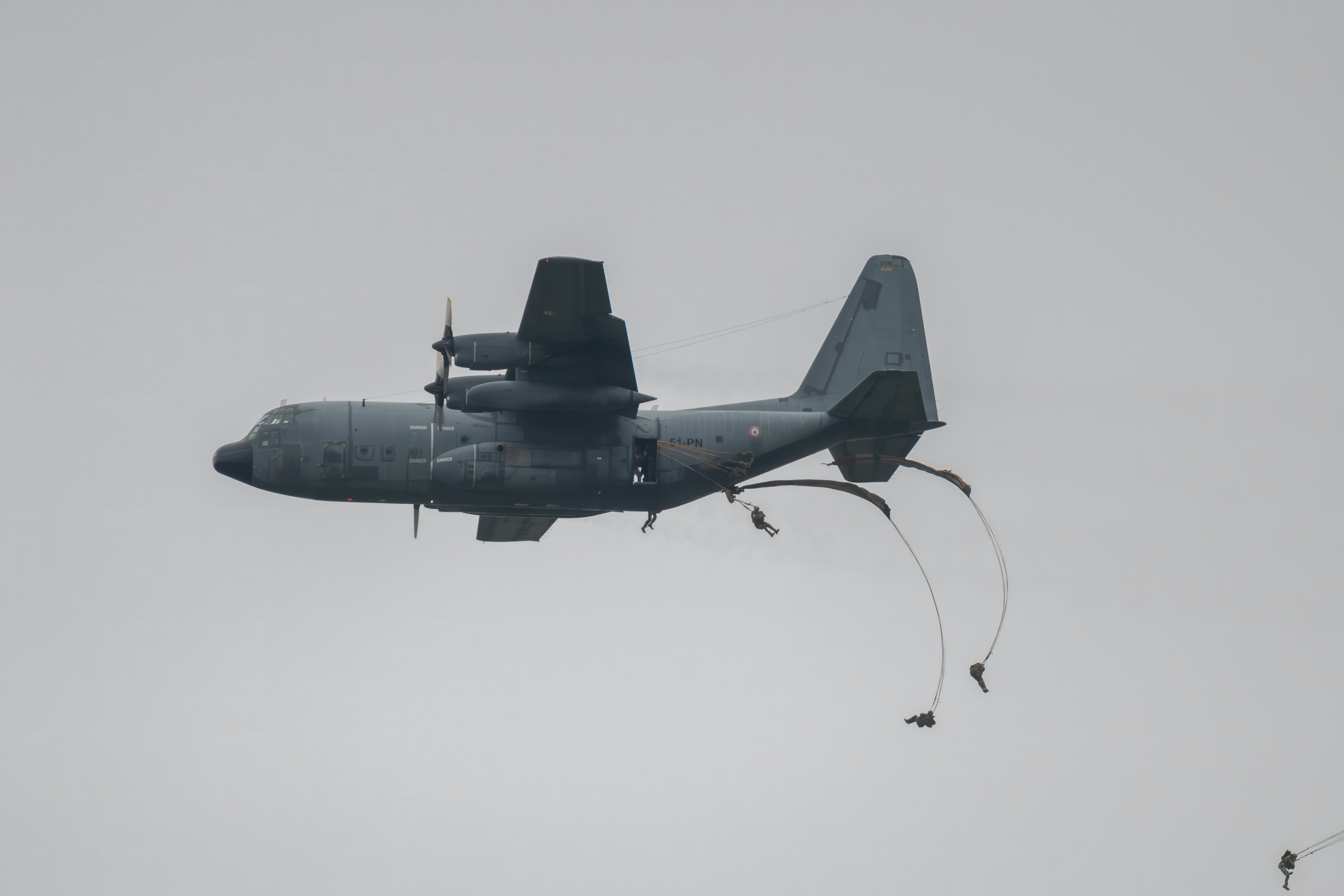 Des parachutistes sautent d’un avion-cargo en vol.