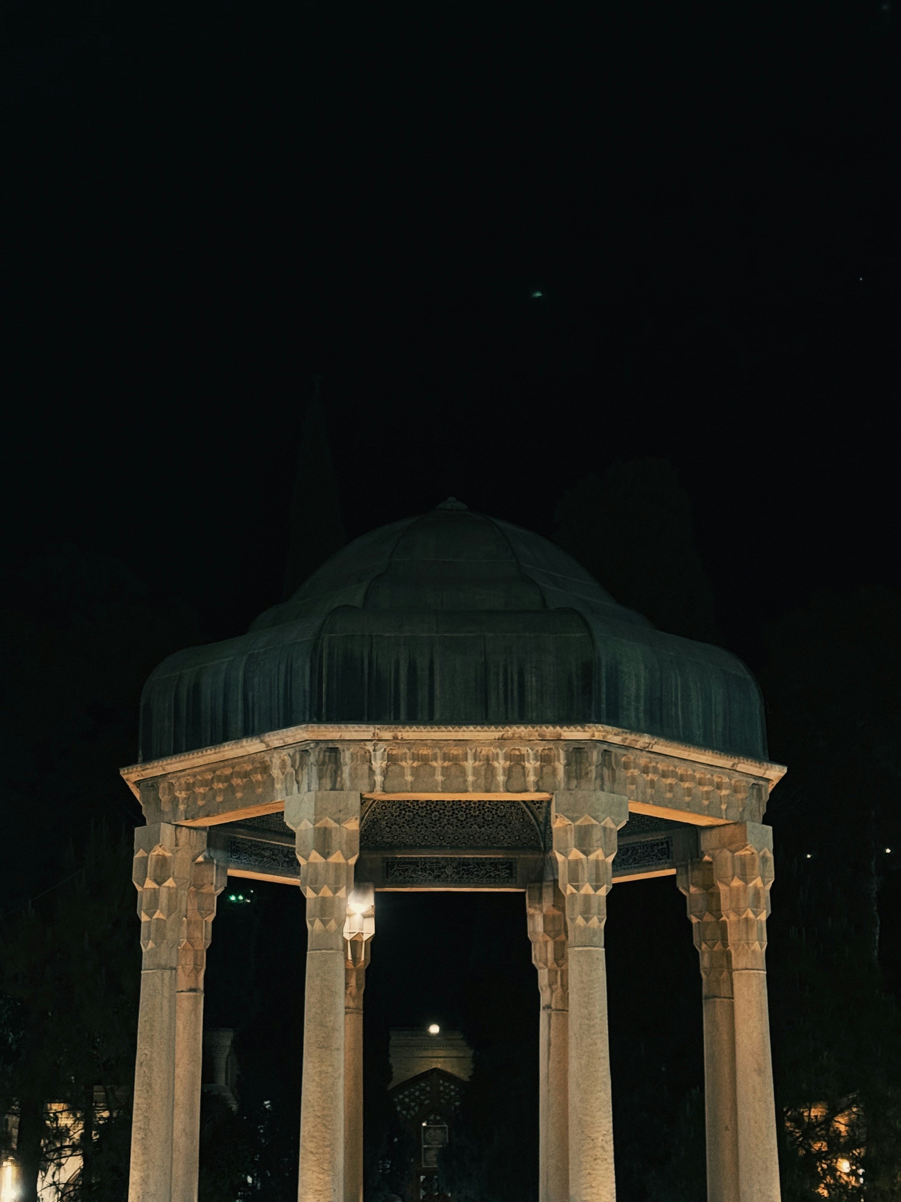 A nighttime shot of a stone gazebo.