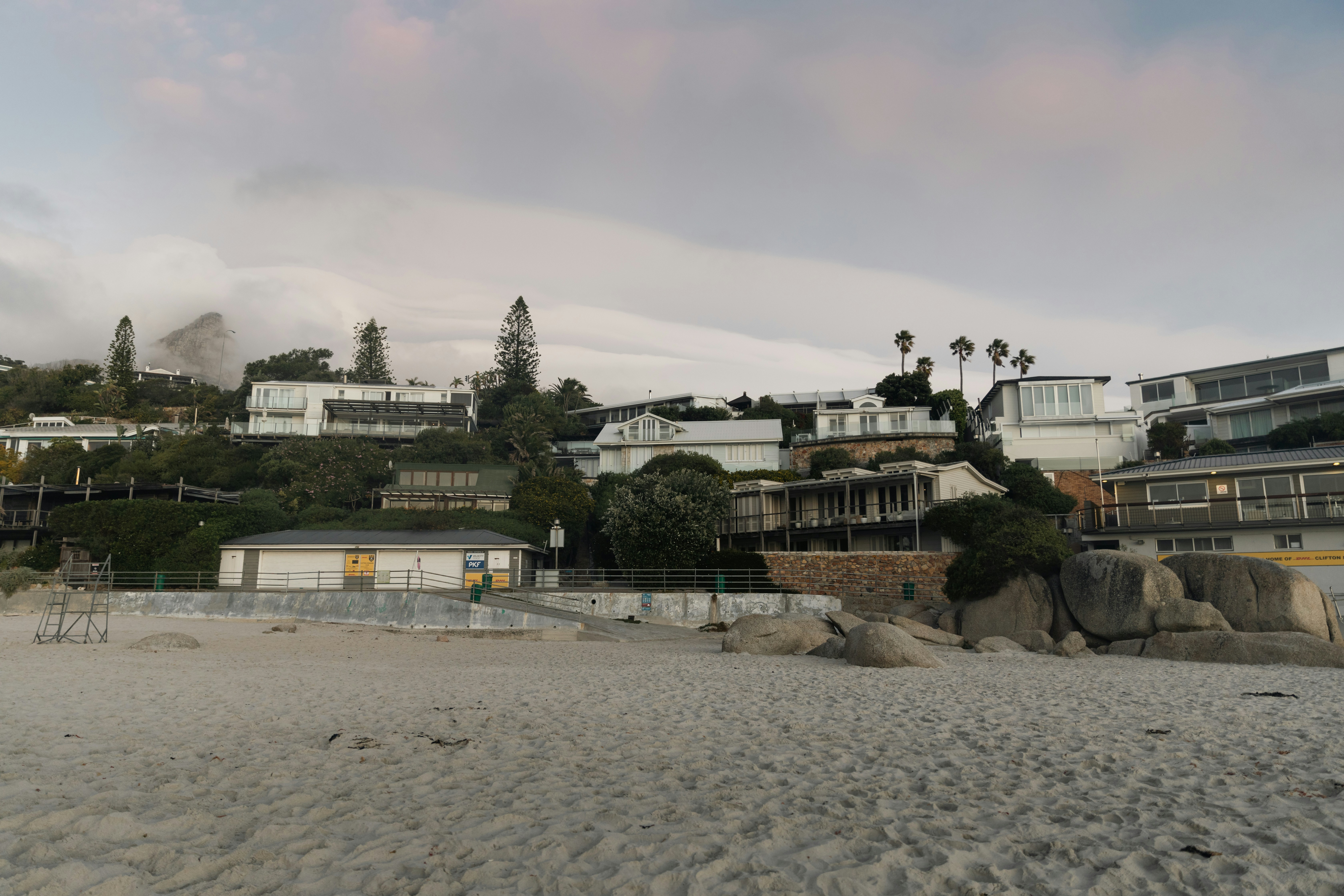 Beach houses line a cloudy coastline.