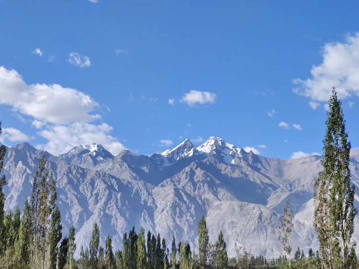 Snowy mountains rise under a bright blue sky.