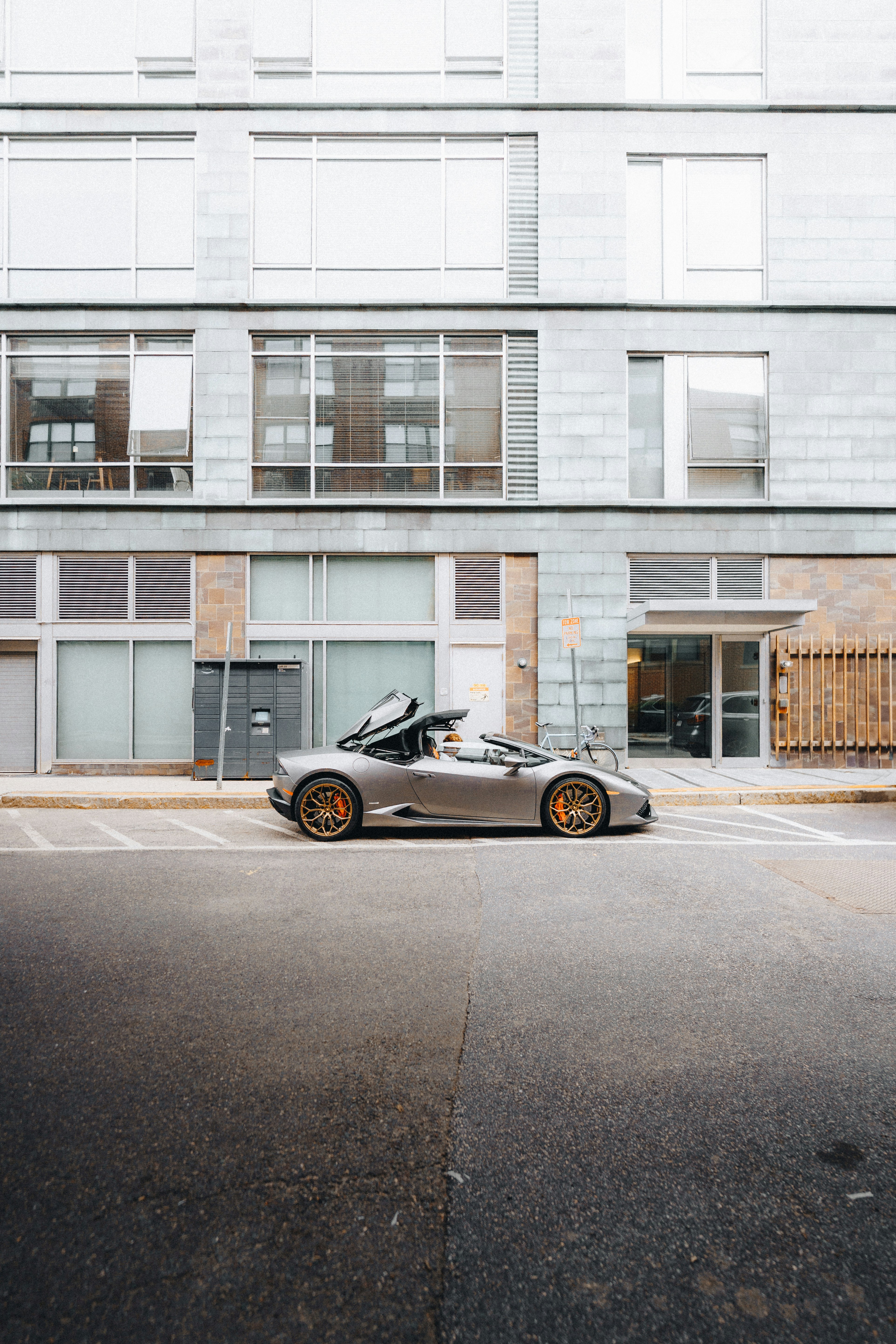 A sleek grey sports car is parked outside.