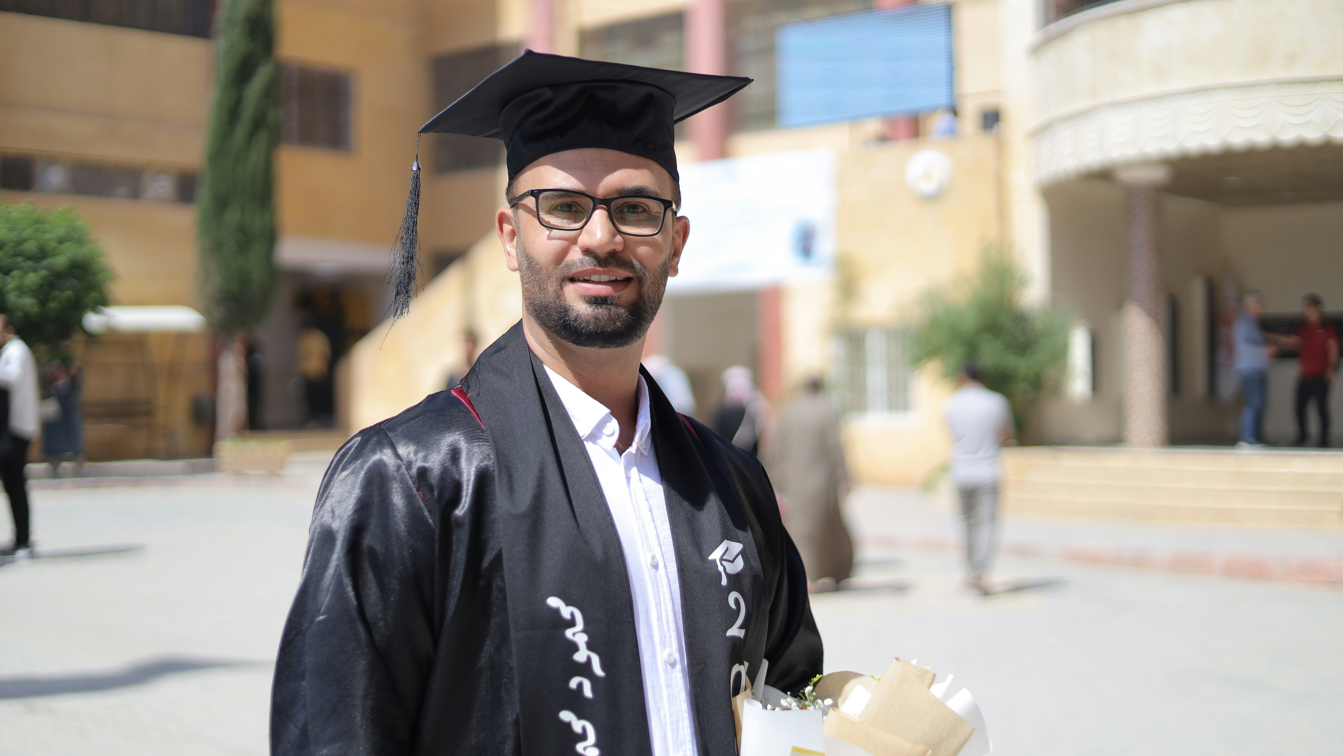 Young man wearing college graduation clothes looking at the camera