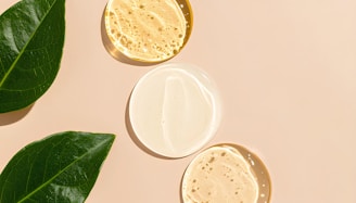 Skincare products with green leaves on a beige surface.