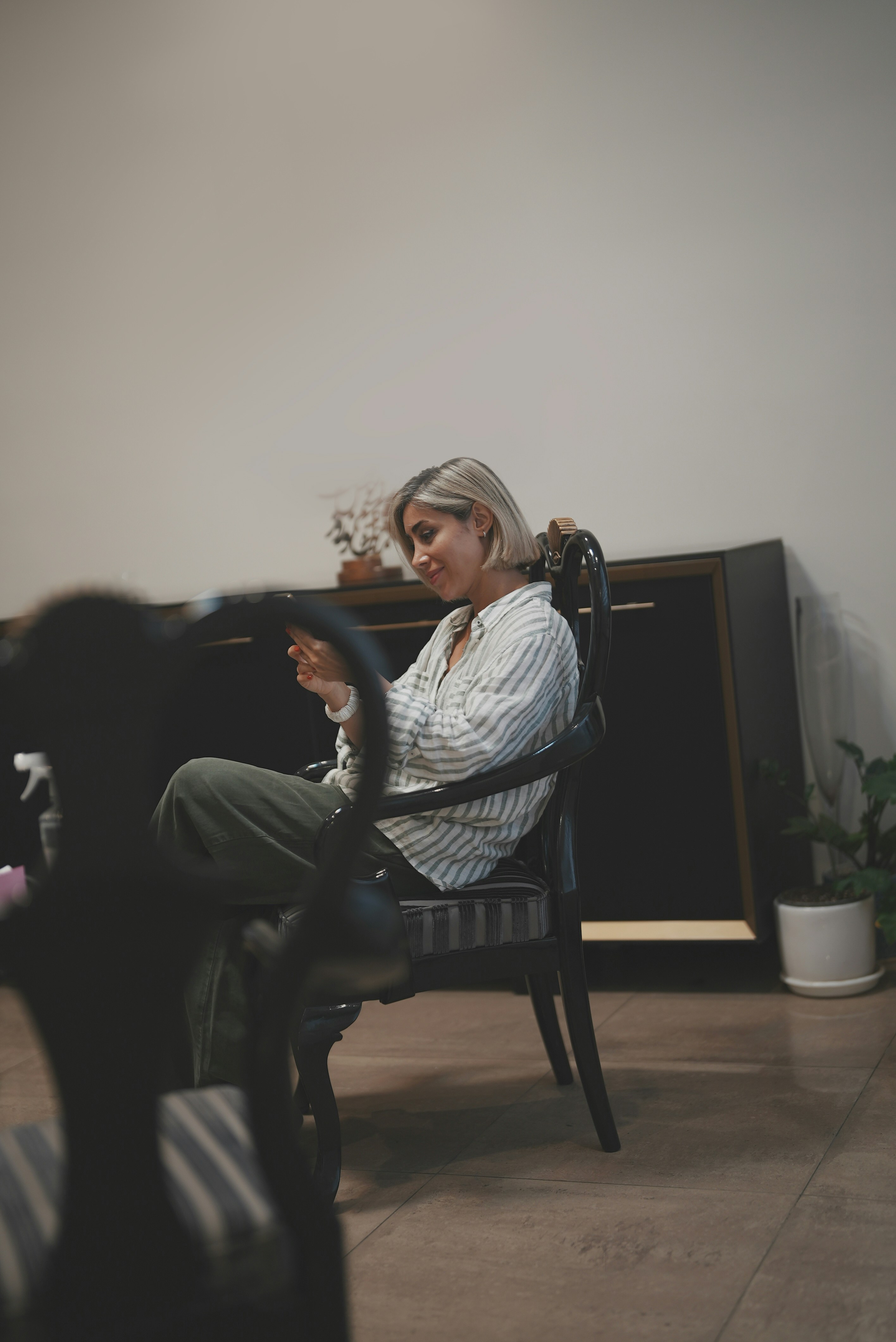 Woman sits and smiles while using her phone.