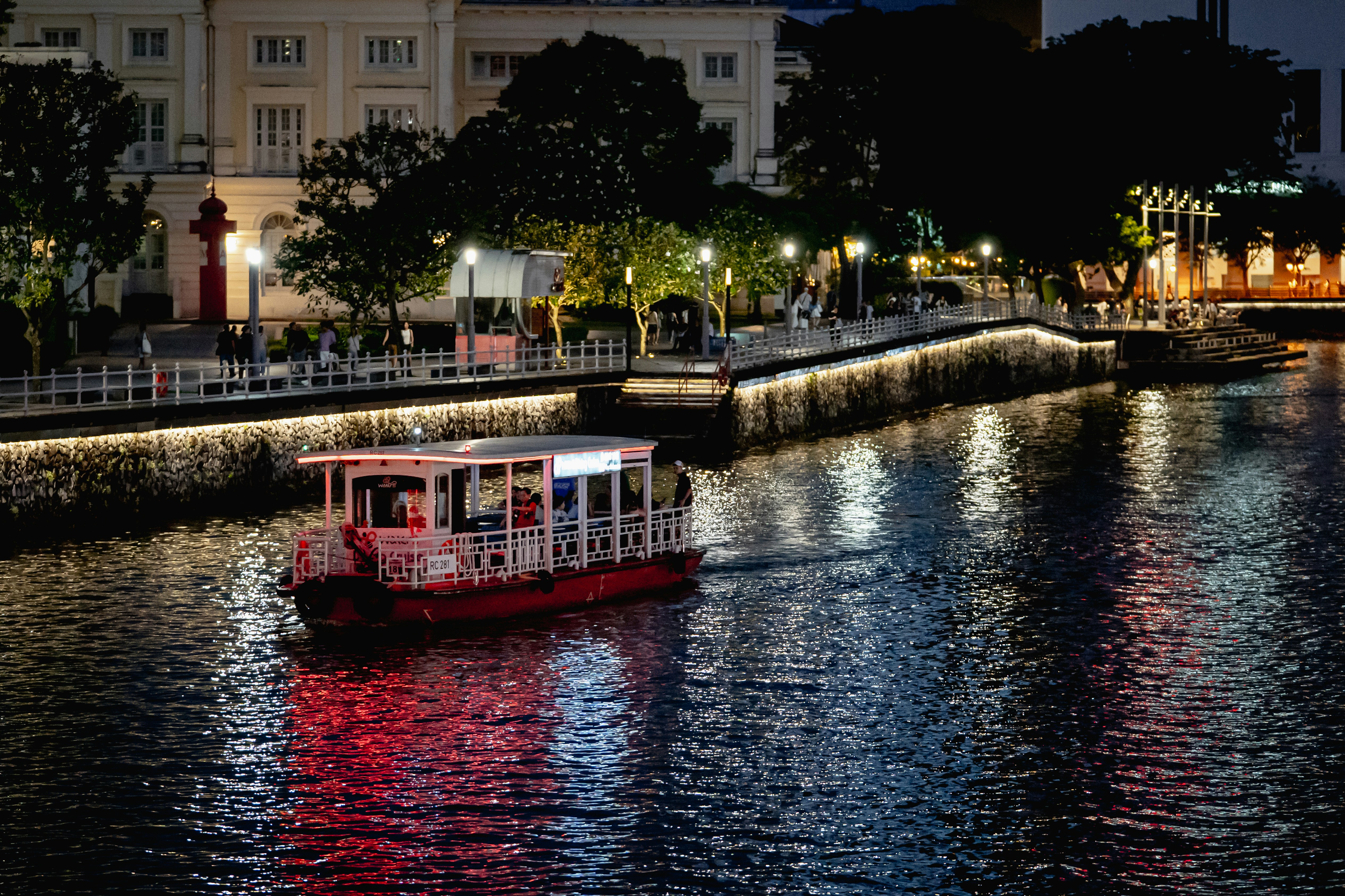 A boat sails along a river at night.
