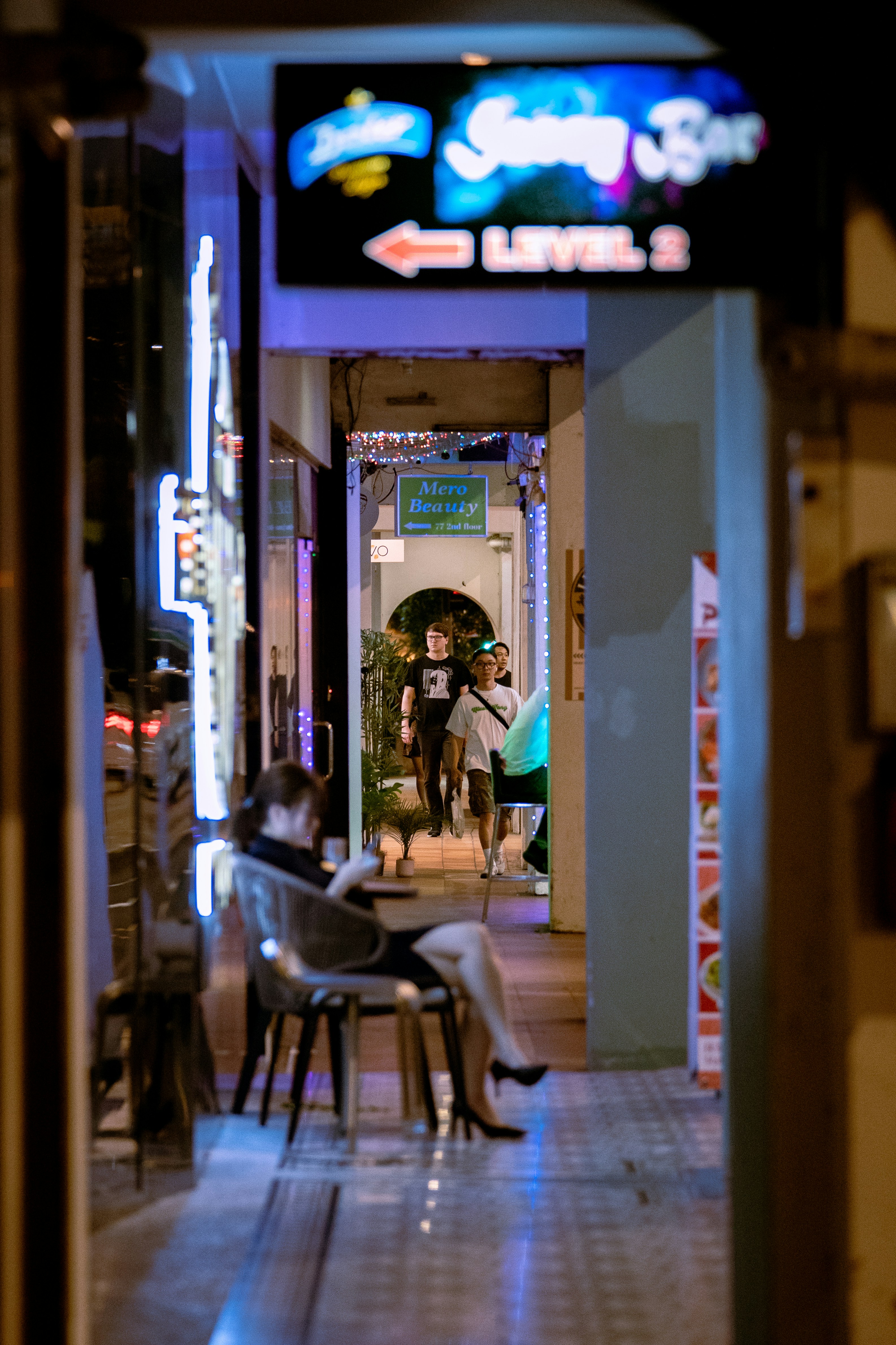 A woman sits outside a bar.
