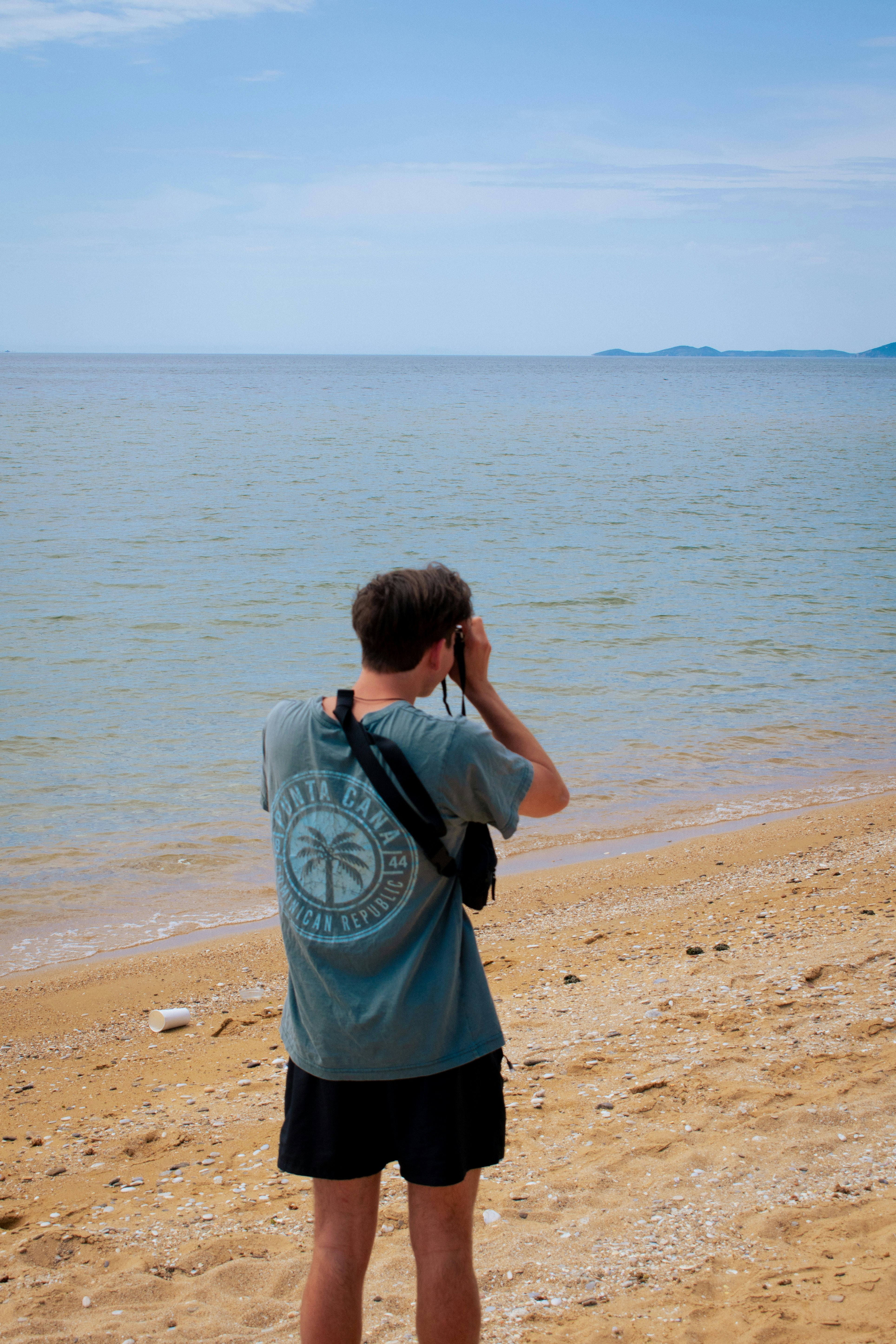 A man takes a photo on a beach.