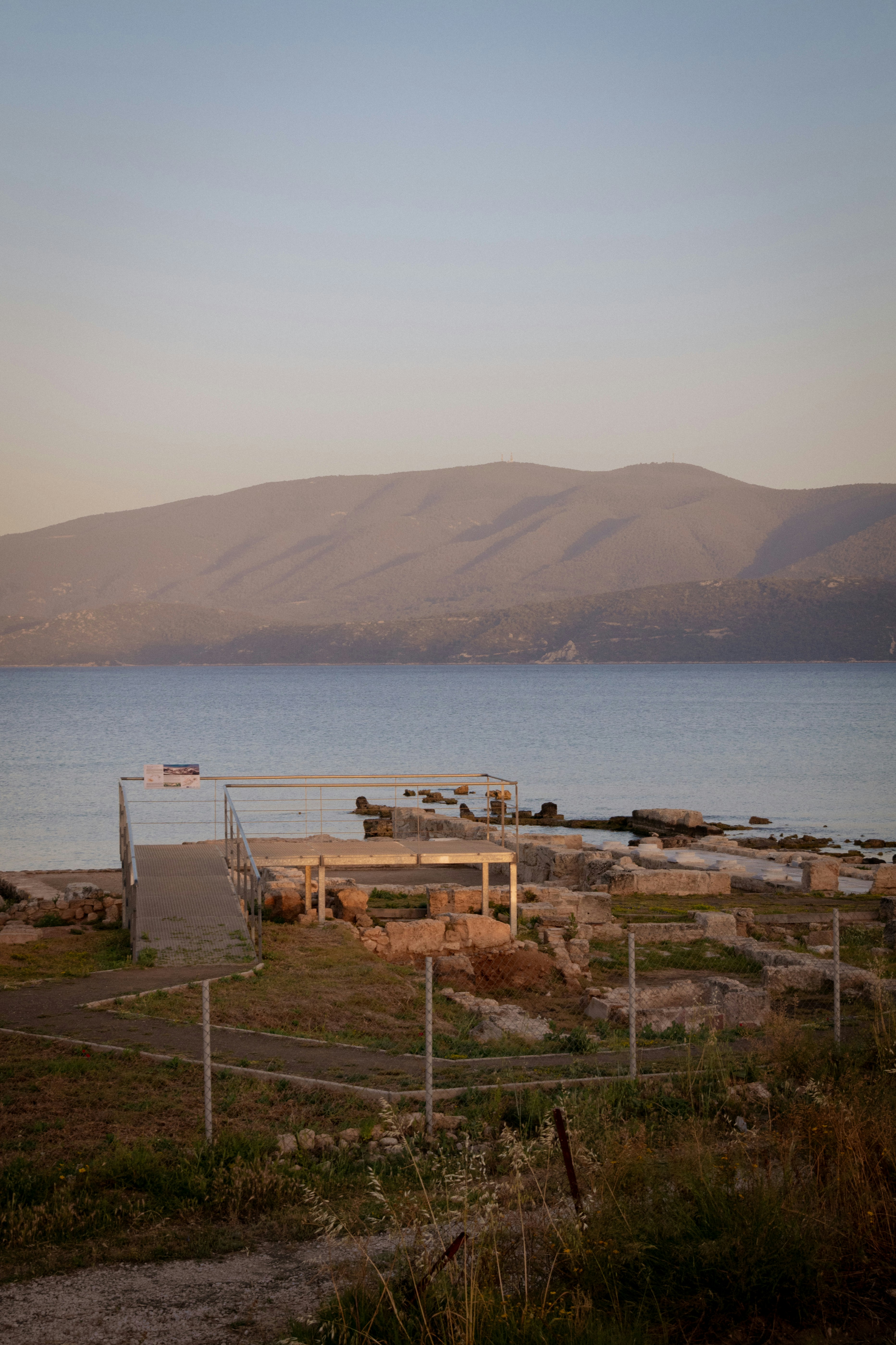 Ruins overlook the sea and distant mountains.