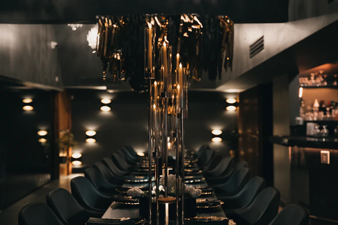 A dark, elegant dining room with long table.