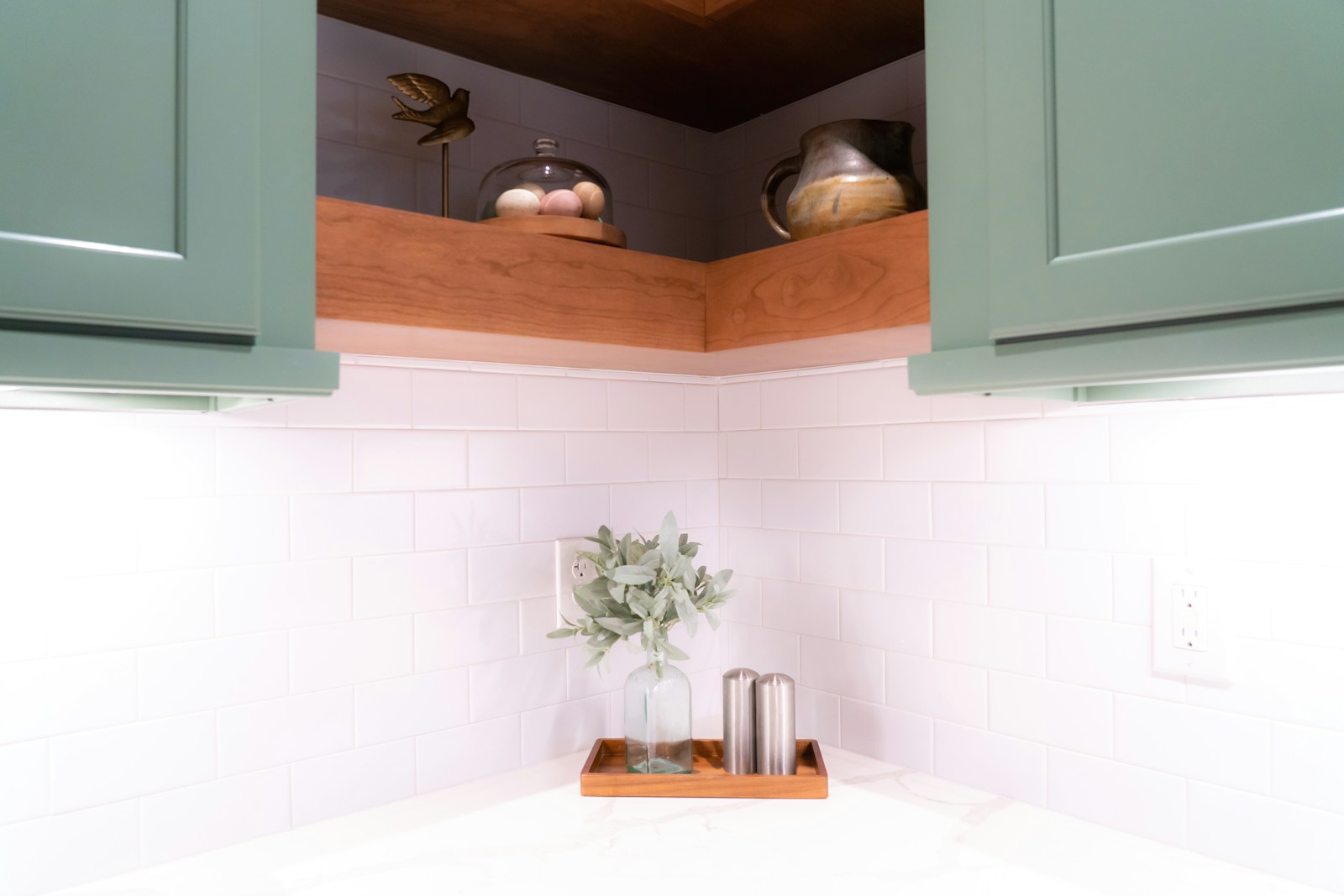 small kitchen corner with green cabinets and open shelf decorations
