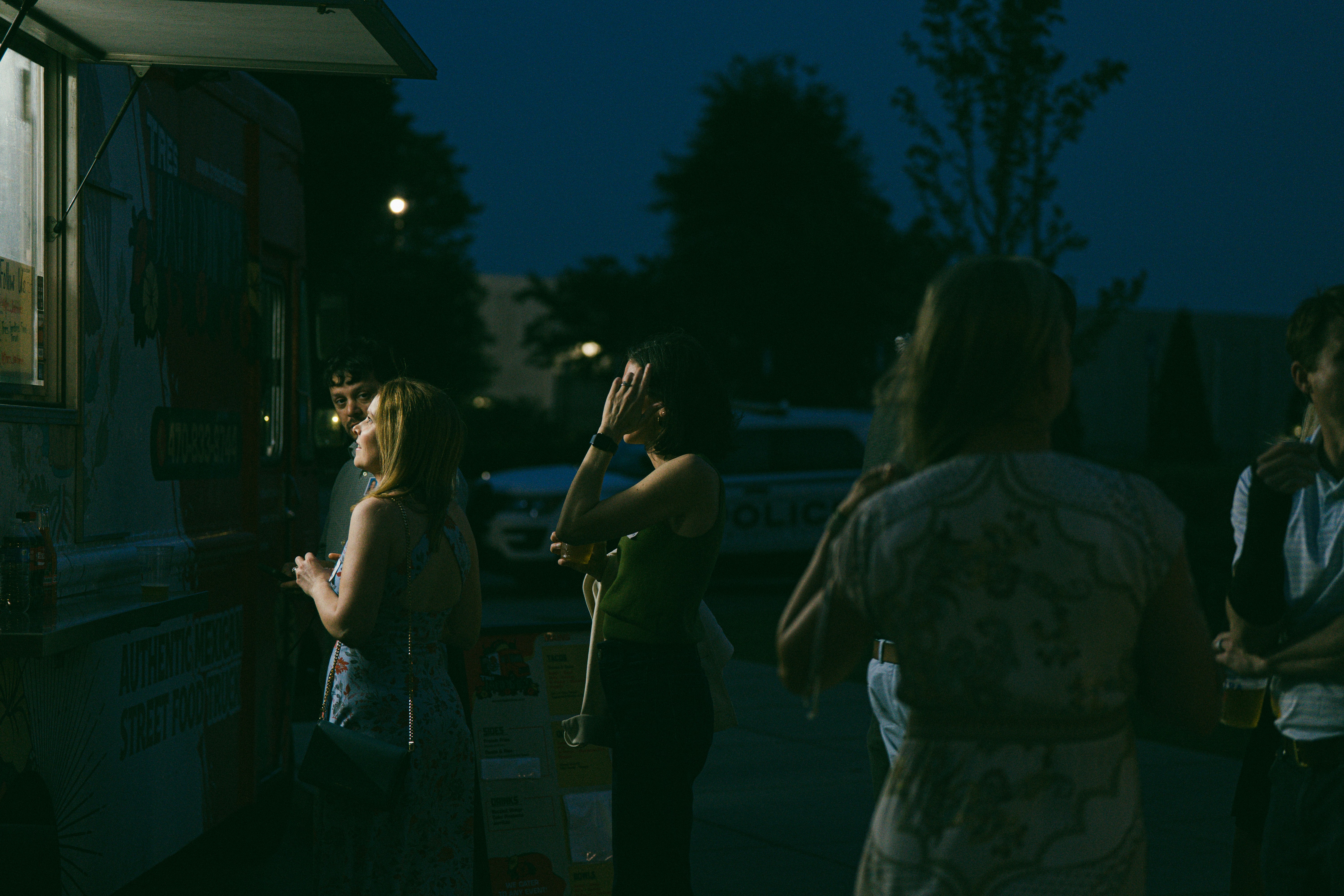 People stand near a food truck at night.