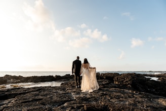 Newlyweds walk towards the ocean.