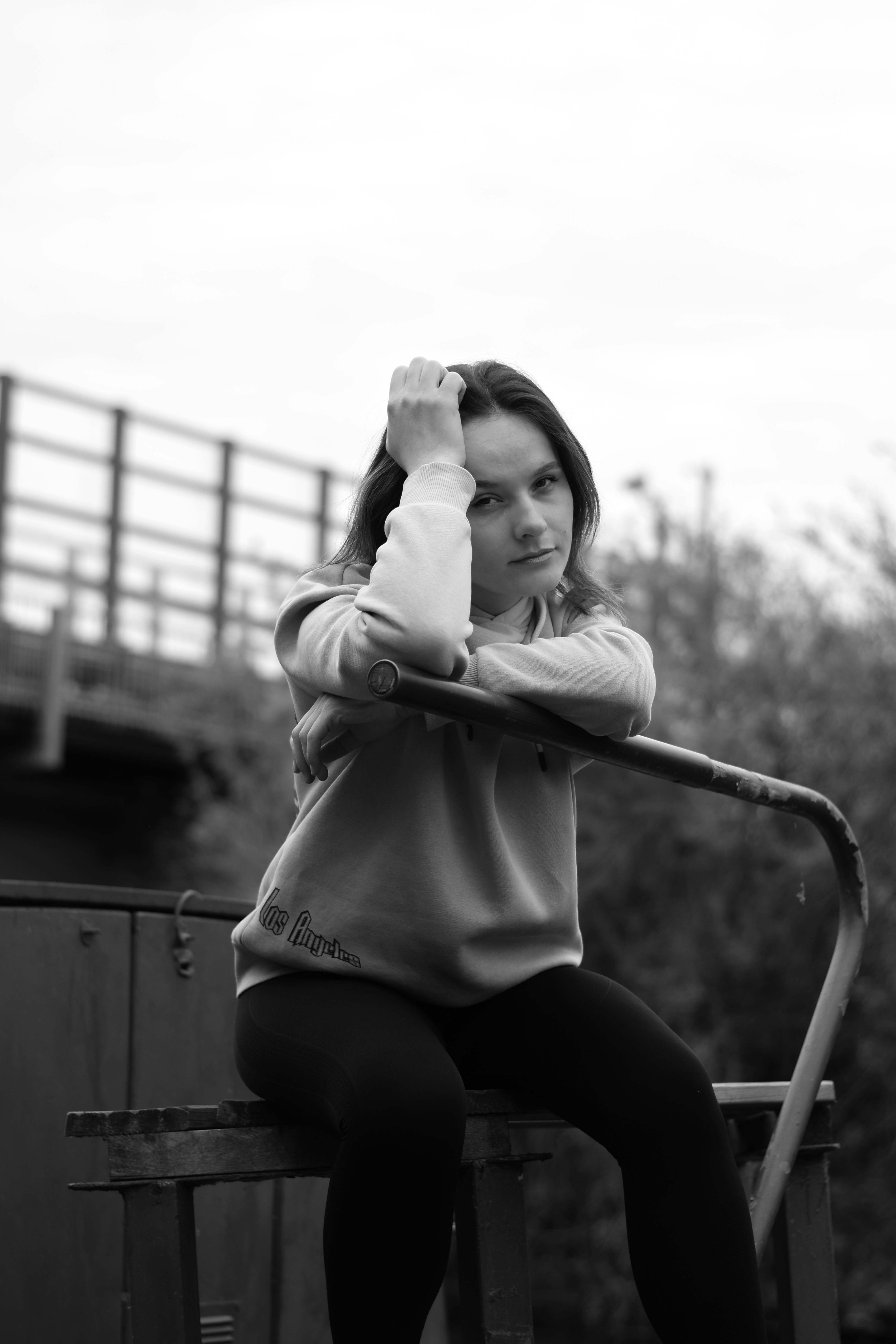 A young woman poses, leaning on a rail.