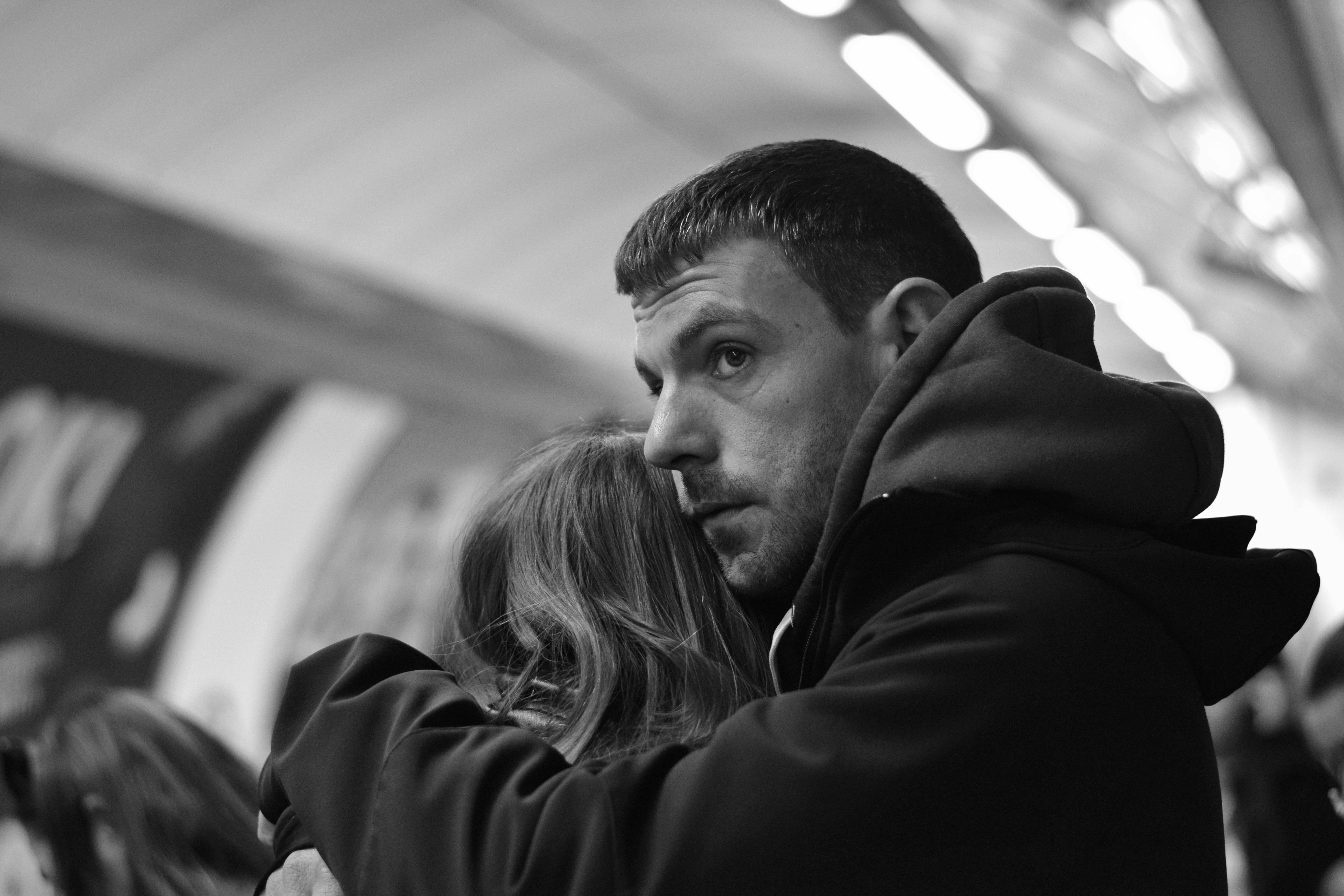 A man with hooded coat looks thoughtfully away.
