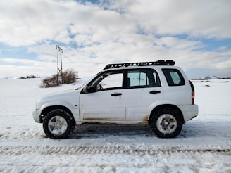 A white suv parks in a snowy landscape.