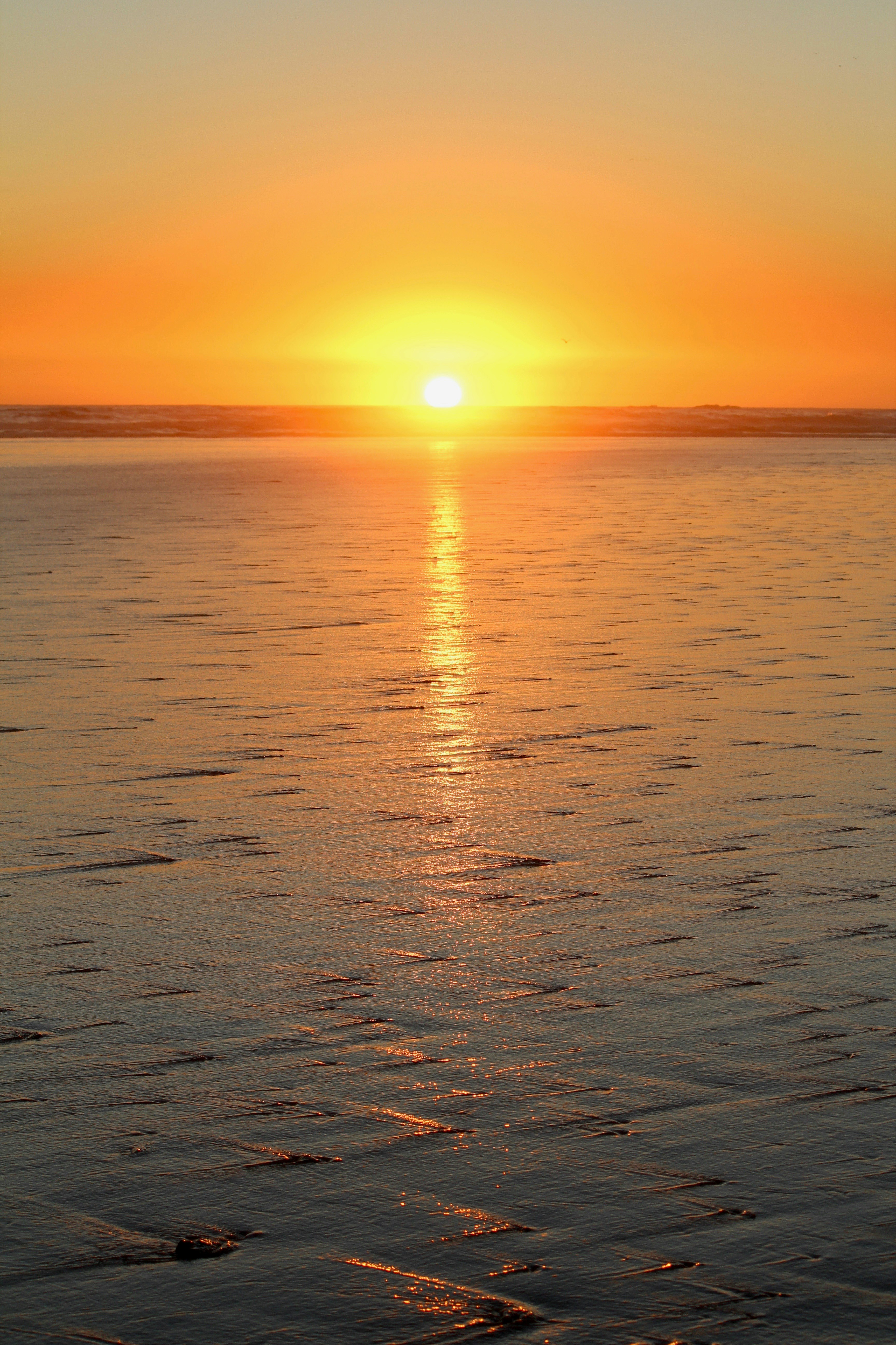 The sun sets over the ocean, creating beautiful colors.