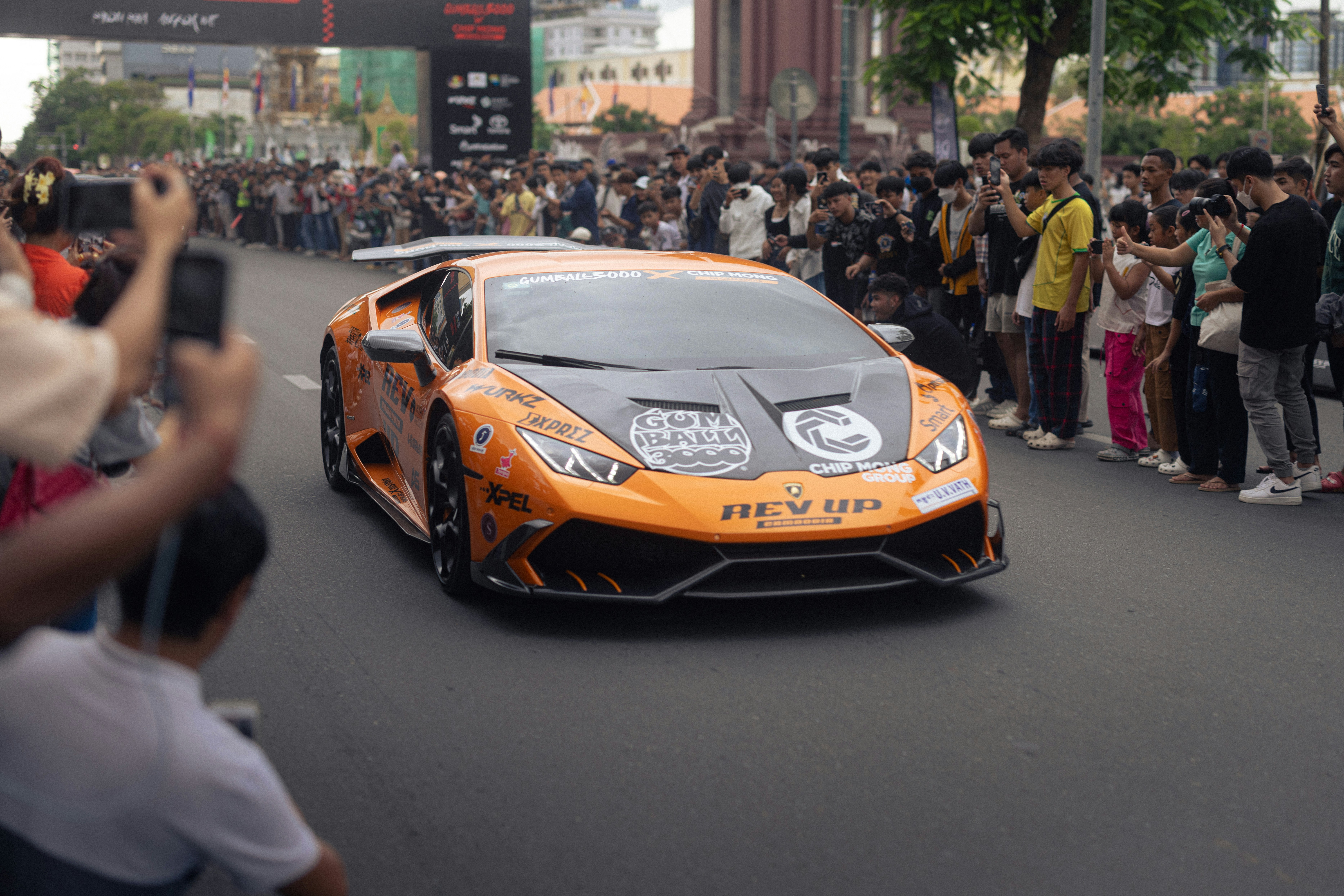 A lamborghini drives through a crowd of people.