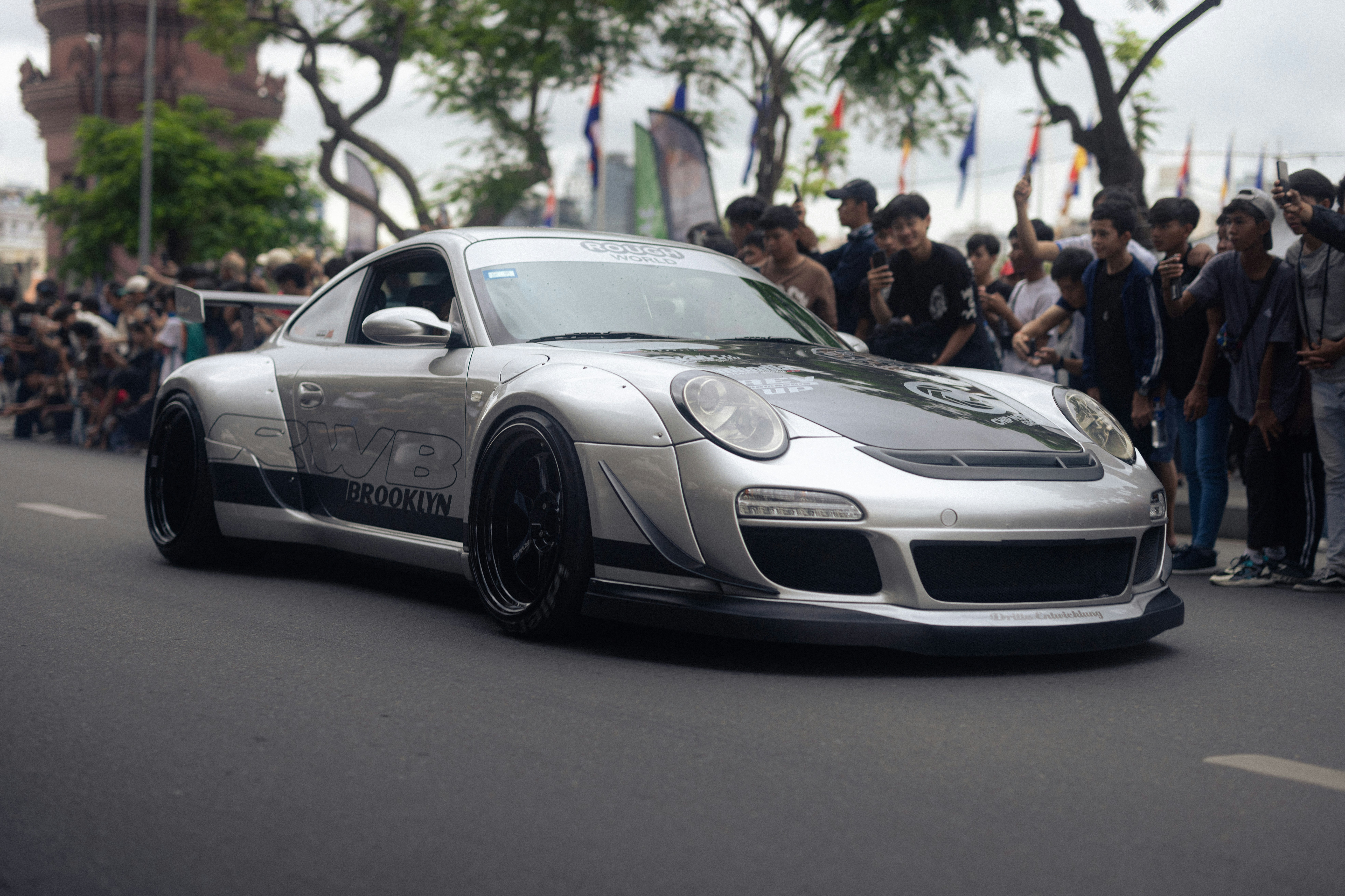 A silver porsche is displayed at a car show.