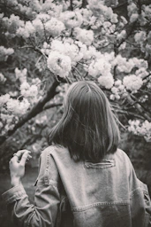 Woman gazes at blooming flowers in black and white.
