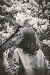 Woman gazes at blooming flowers in black and white.